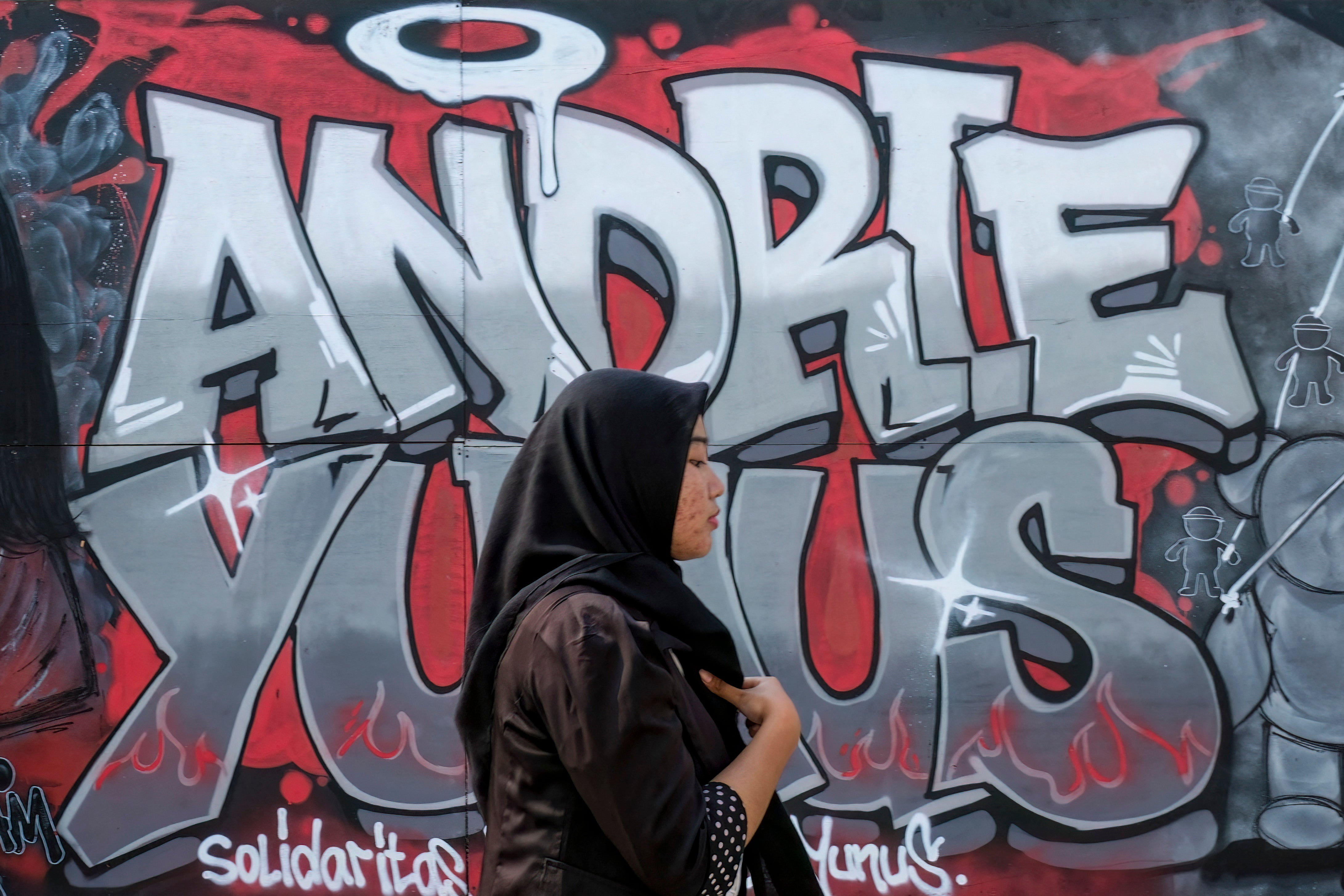 A visitor walks past a mural featuring the name of Andrie Yunus, the deputy coordinator of the KontraS rights group who suffered serious injuries when two men on a scooter threw acid at him, at the Mural Exhibition 