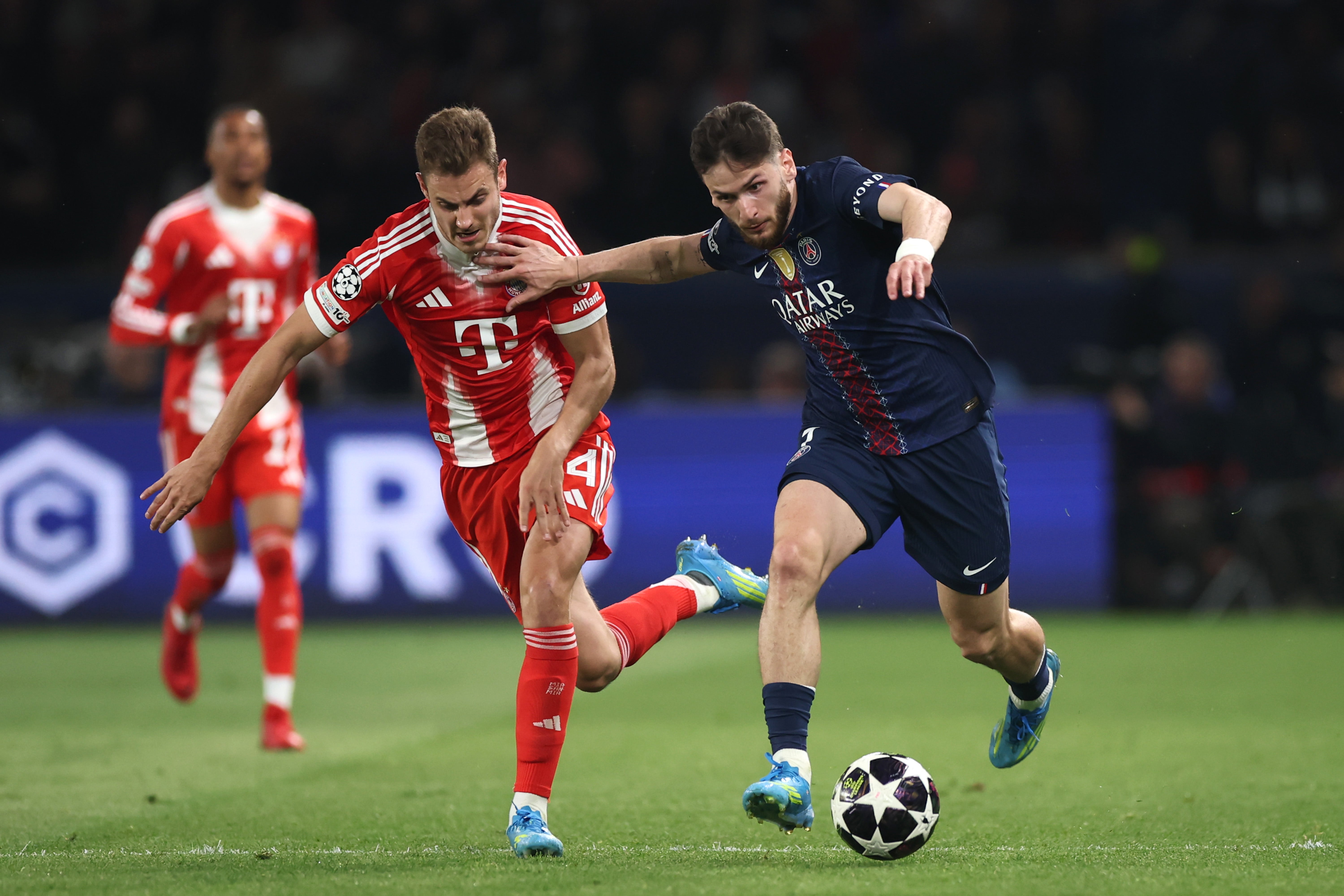 Aleksandar Pavlovic of FC Bayern Munich is challenged by Khvicha Kvaratskhelia of Paris Saint-Germain