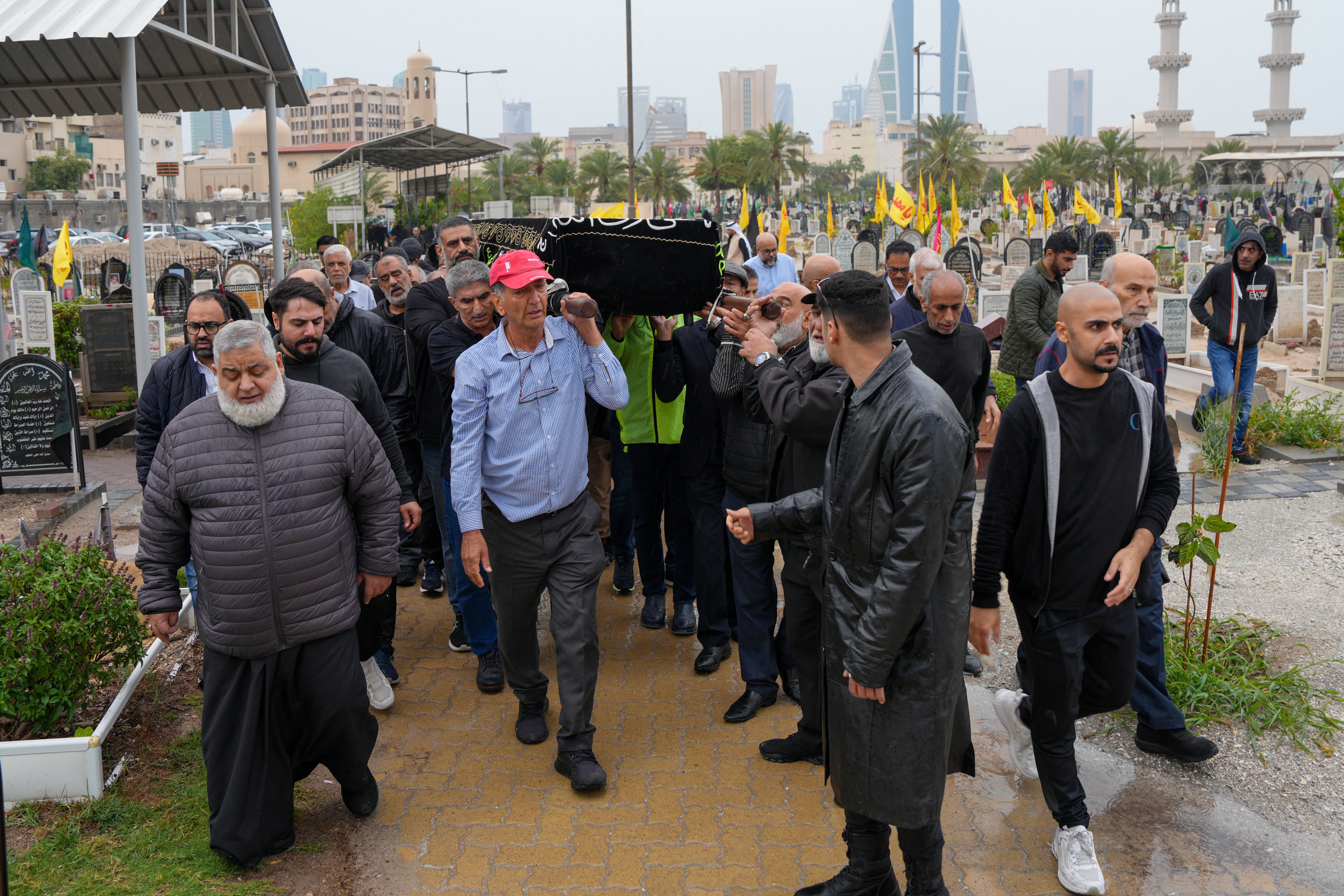 People carry the coffin of a person killed during a drone attack on a high-rise apartment building in Bahrain's capital Manama to its grave during the burial on 10 March 2026