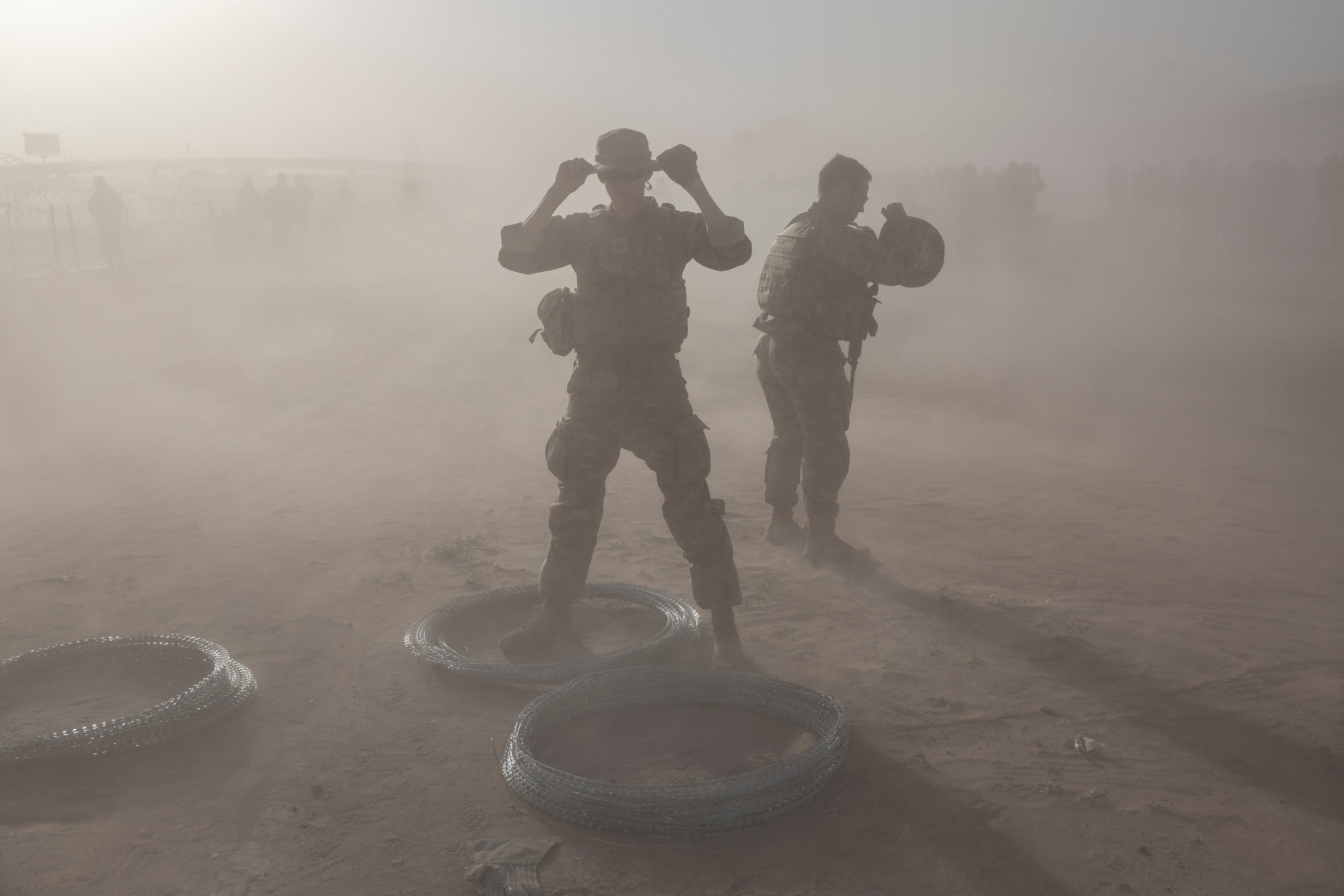 Texas National Guard soldiers uncoil razor wire during a dust storm in El Paso at the U.S. Mexico border fence in May 2023. The border city is frequently hit by dust storms that researchers say are fueling higher rates of Valley Fever