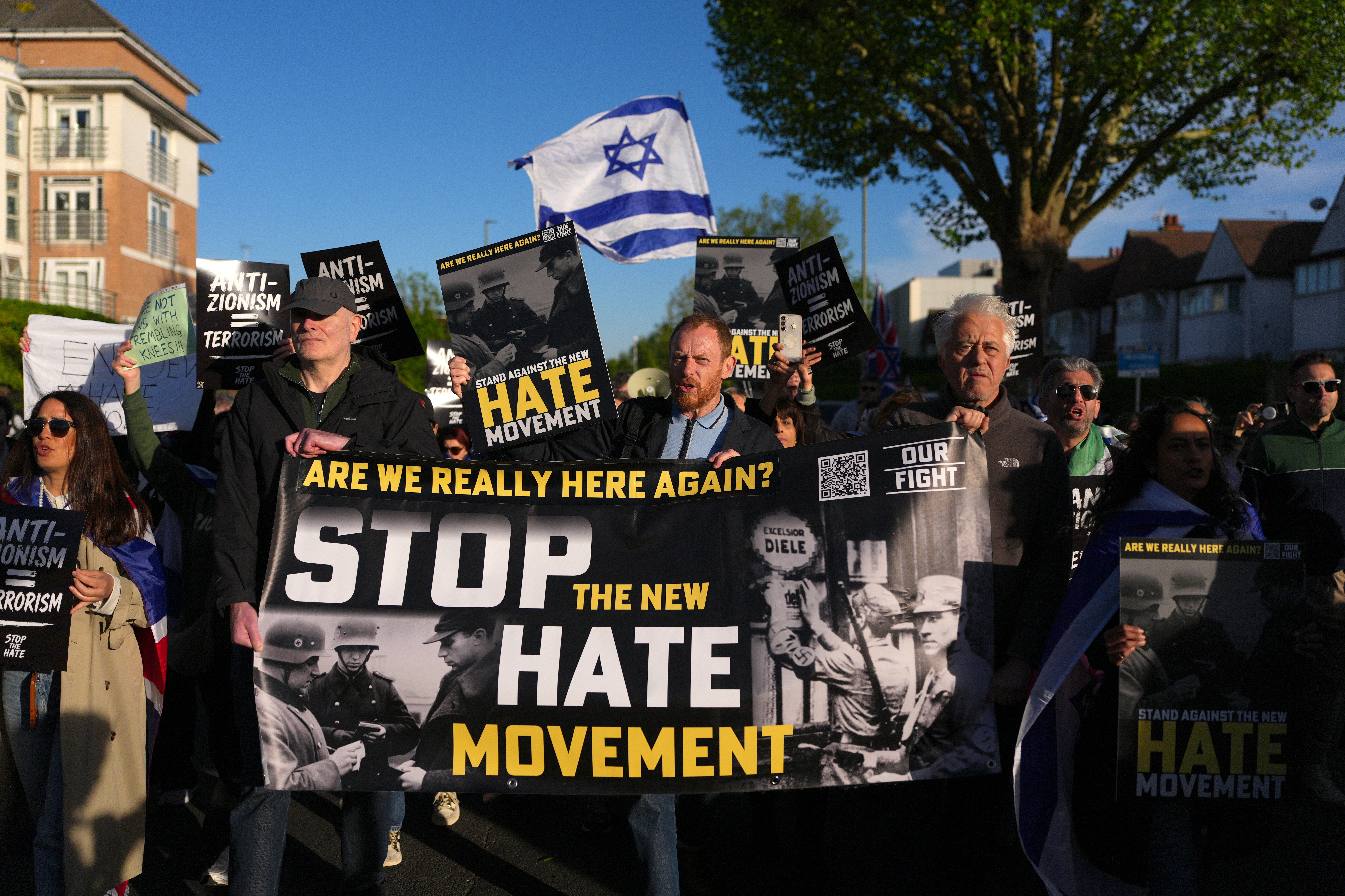 People participate in a Stop the Hate protest near the crime scene