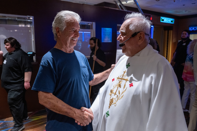 <p>El padre Charlie Urnick saluda a un feligrés con un apretón de manos tras la misa en el Riverside Casino de Laughlin, Nevada</p>