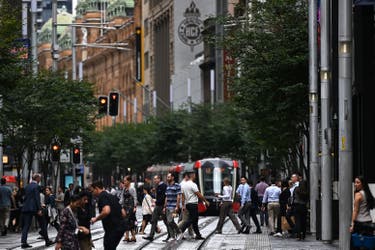 <p>People walk along George Street in Sydney</p>