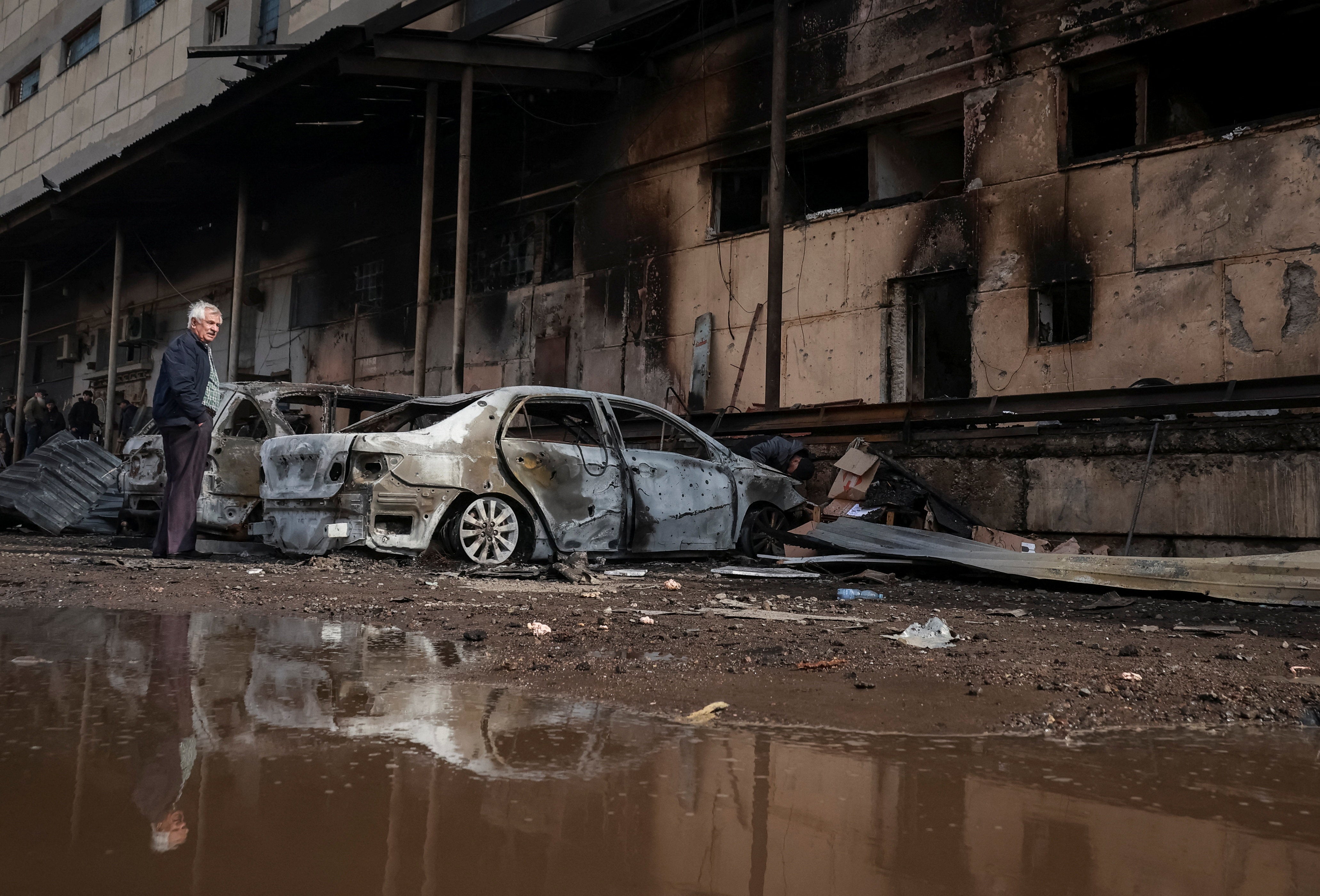 A resident stands next to his destroyed car at the site of a Russian drone strike in Odesa