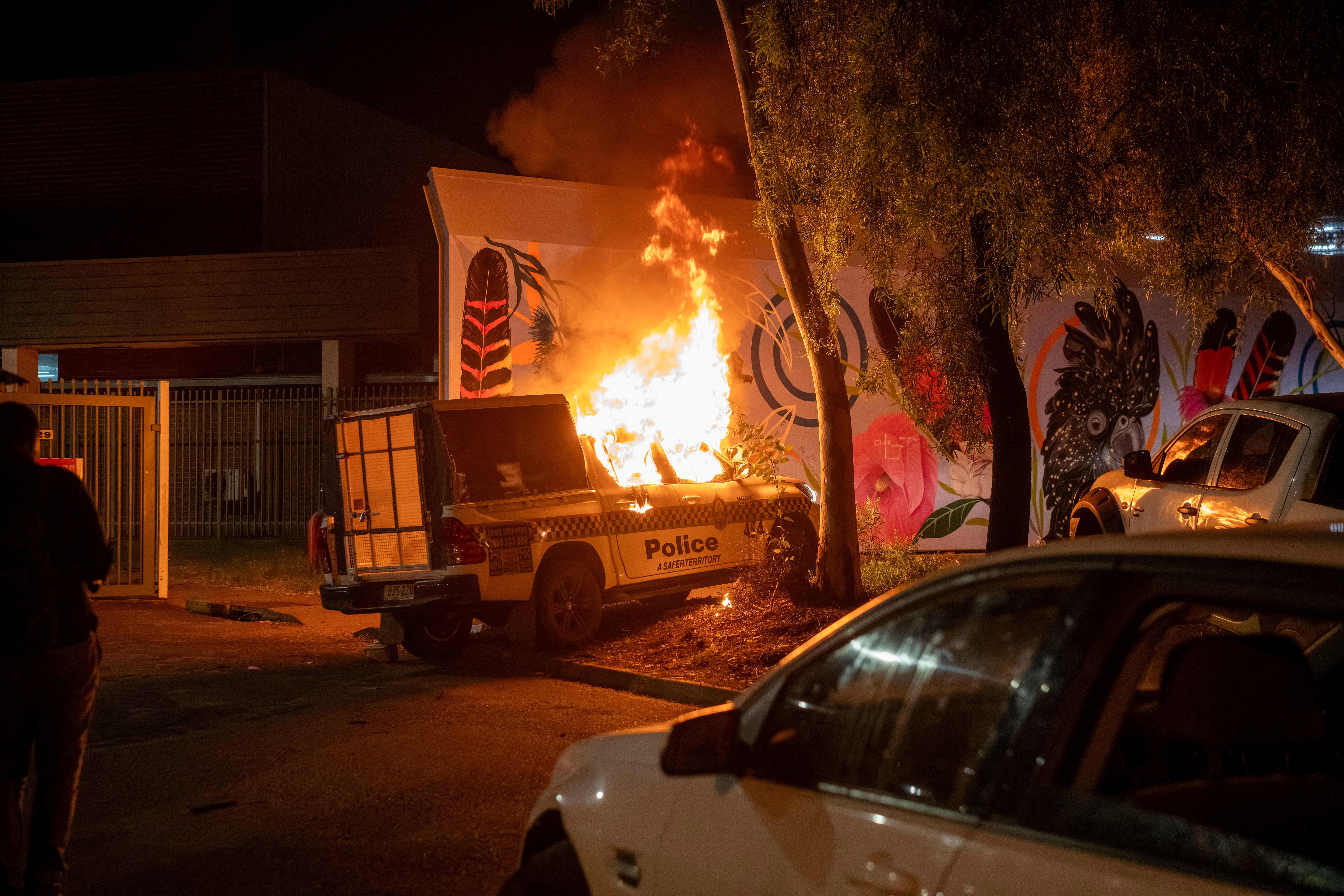 A police vehicle burns after community members clashed with police outside Alice Springs Hospital in Australia