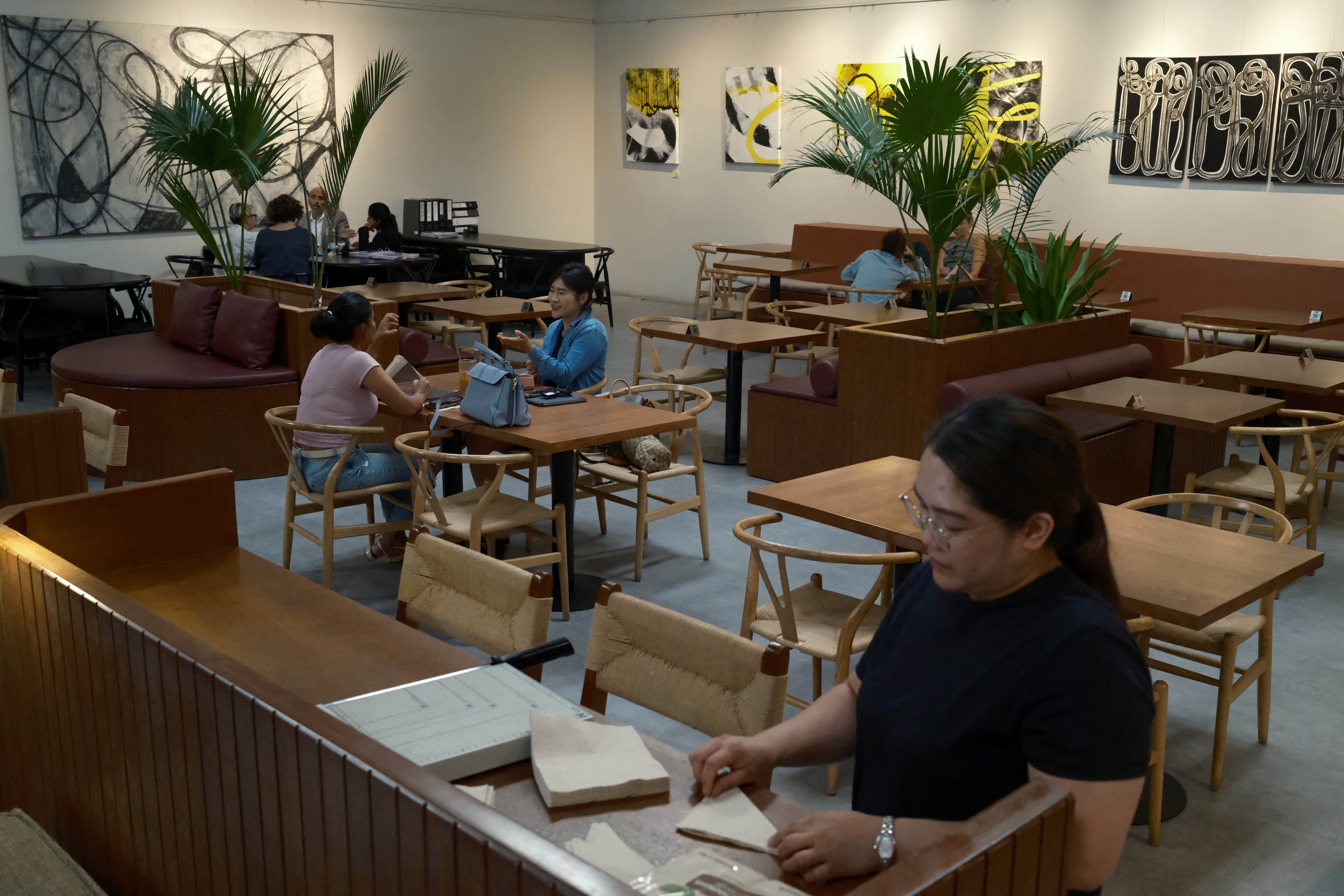 An employee folds napkins while diners sit in the background, at Lila Molino restaurant, in Dubai, United Arab Emirates, April 28, 2026. REUTERS