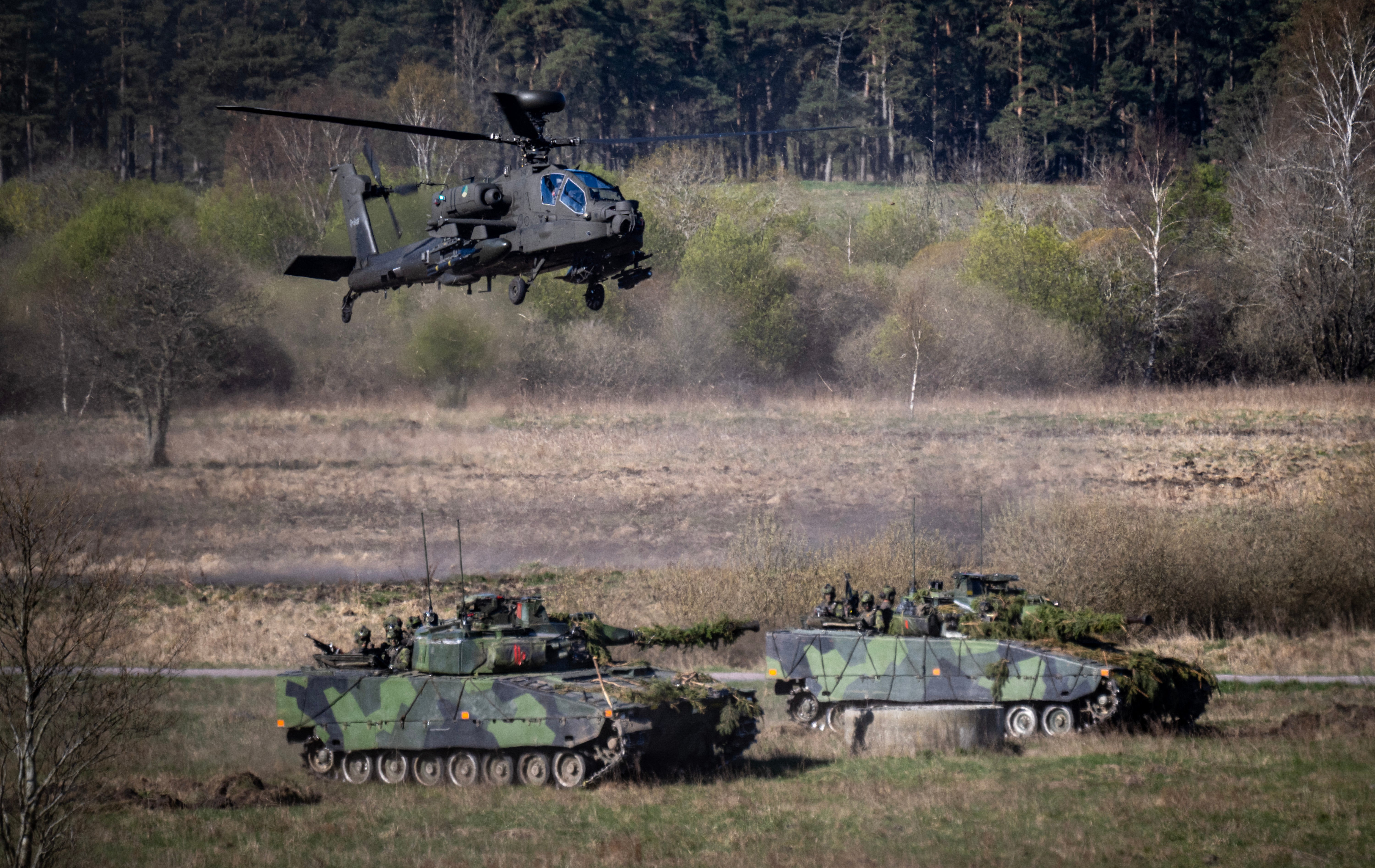 A Dutch Boeing AH-64 Apache attack helicopter flies over 2 Swedish Stridsfordon 90 tracked armoured combat vehicles as the Nato allies take part in a combat display during press day for the military exercise Aurora 26 at the Revingehed training field outside Lund in Skane, Southern Sweden on April 29, 2026