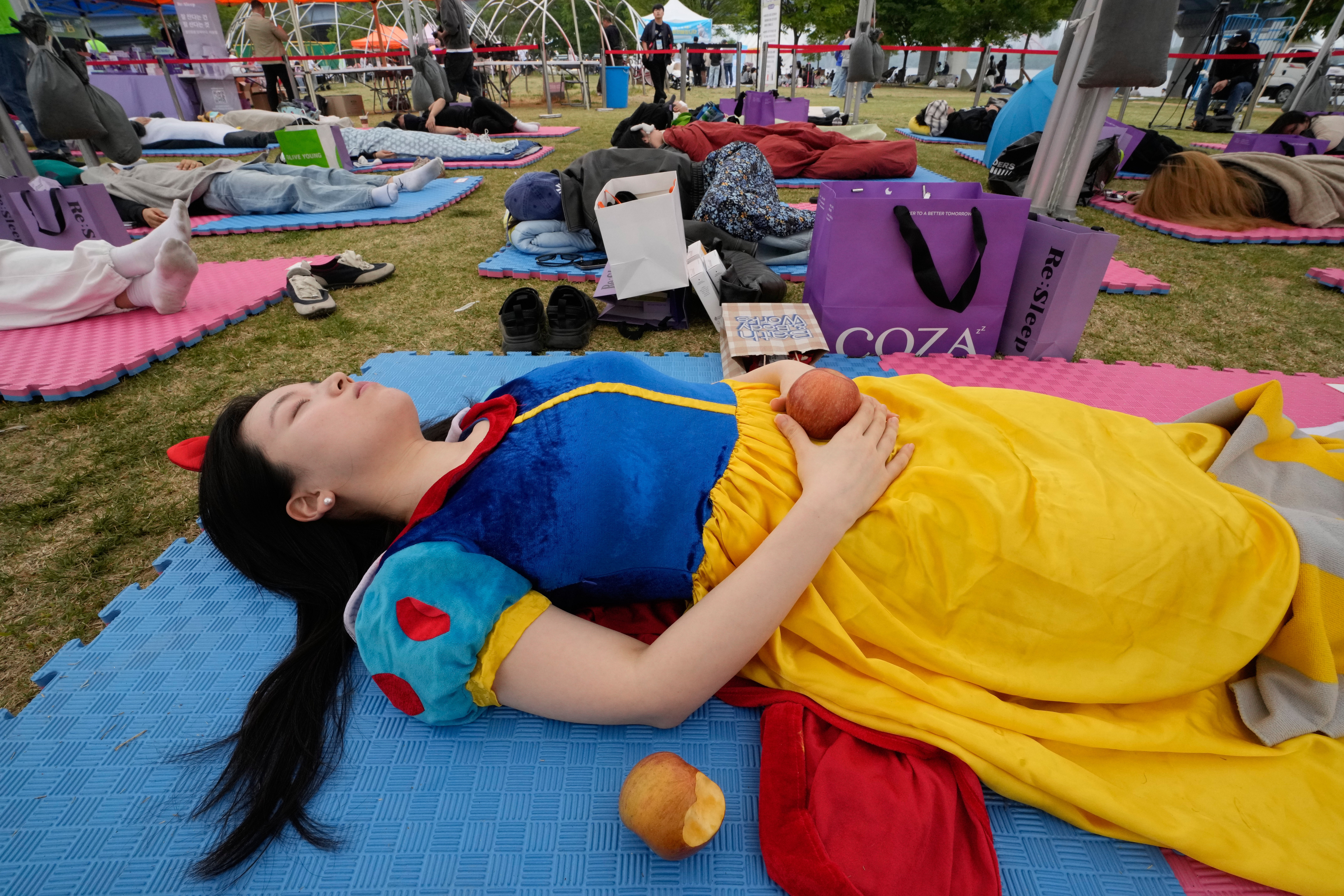 A participant dressed as Snow White takes a nap during the 2026 Hangang Nap Competition