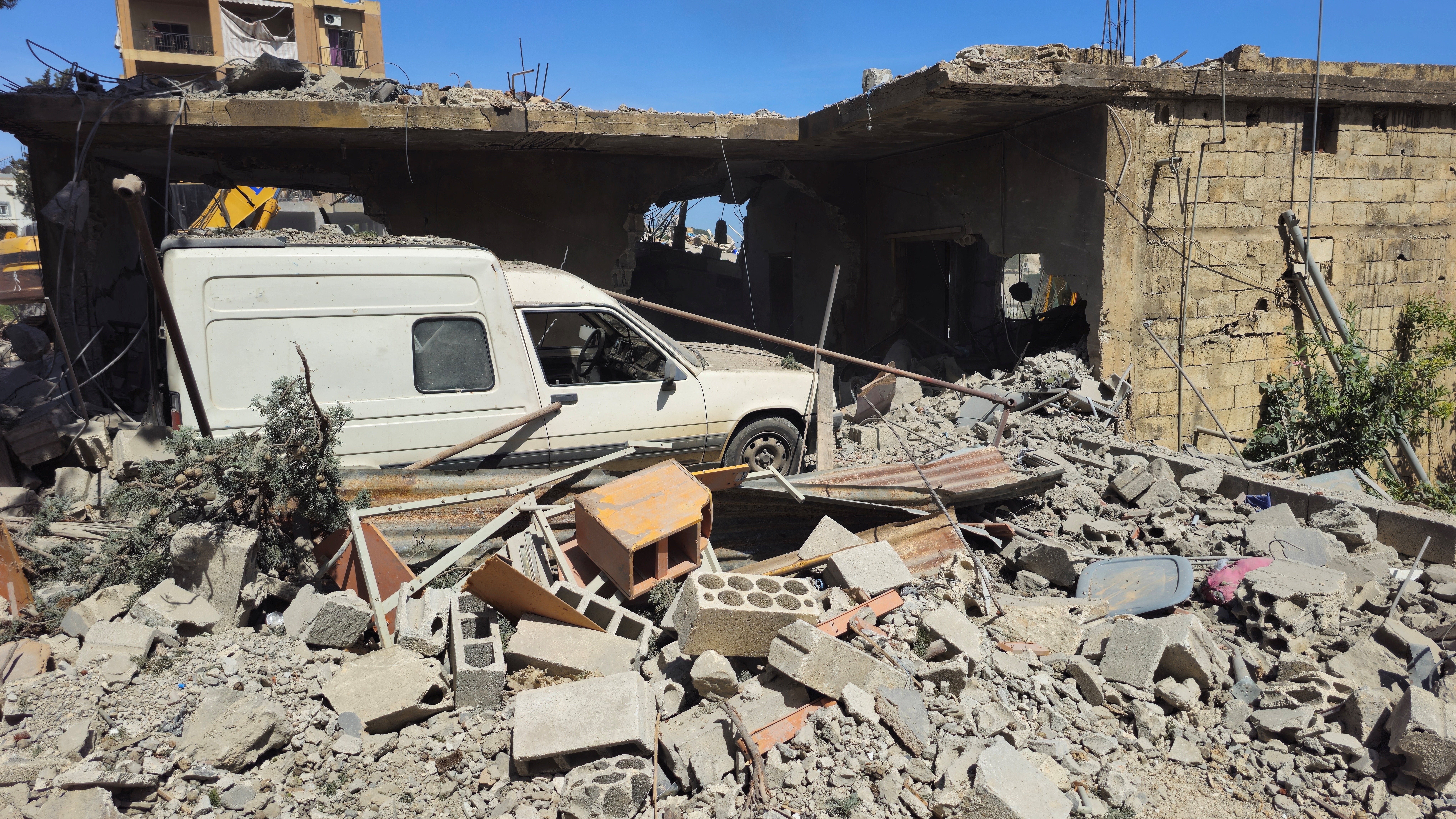 A vehicle remains trapped amid the rubble of a destroyed building