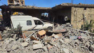 A vehicle remains trapped amid the rubble of a destroyed building