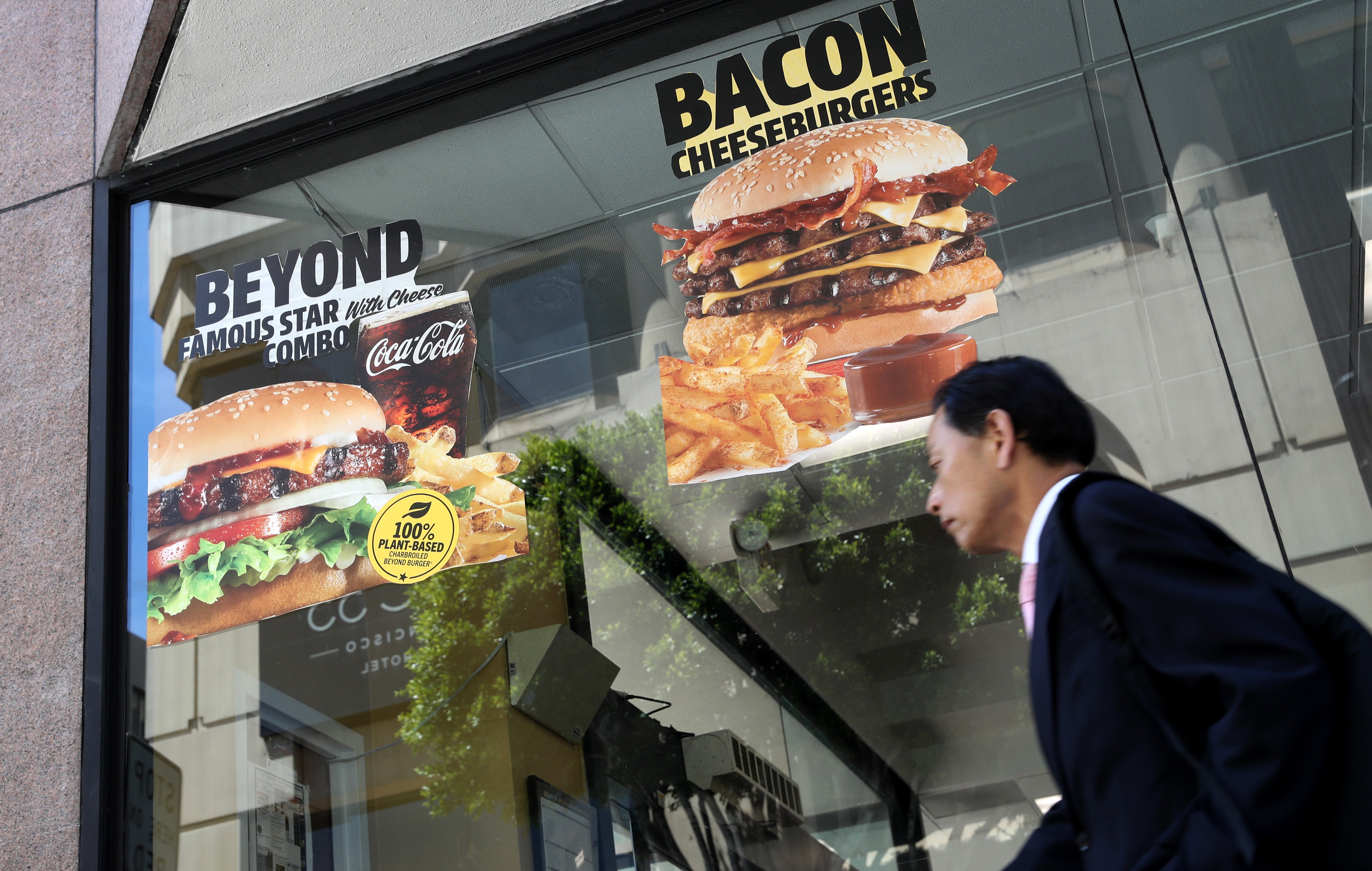 <p>A pedestrian walks by an advertisement for meat burger</p>