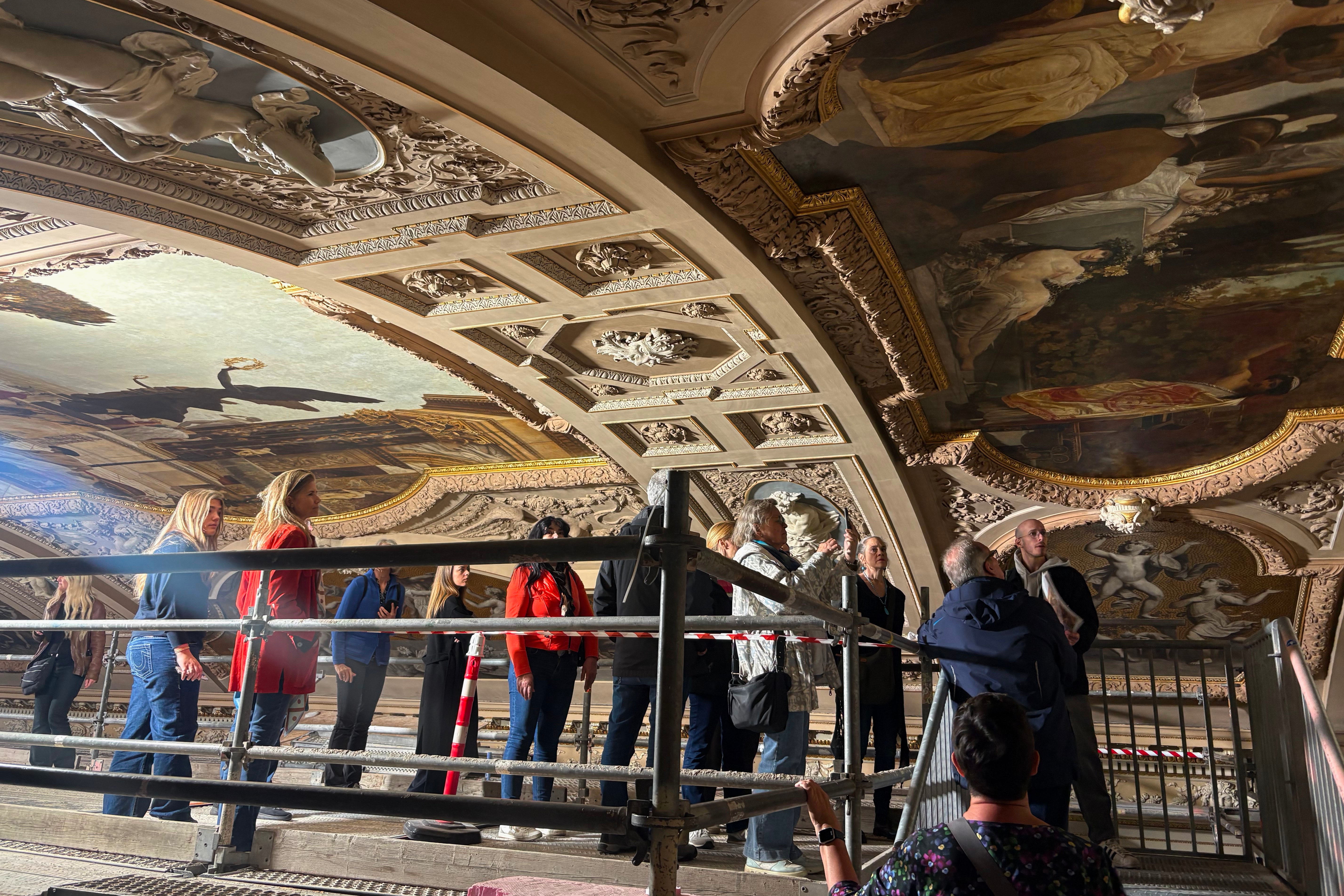 People look at a restored painting of Gustav Klimt during a guided tour of the restoration of the ceiling paintings at the Burgtheater