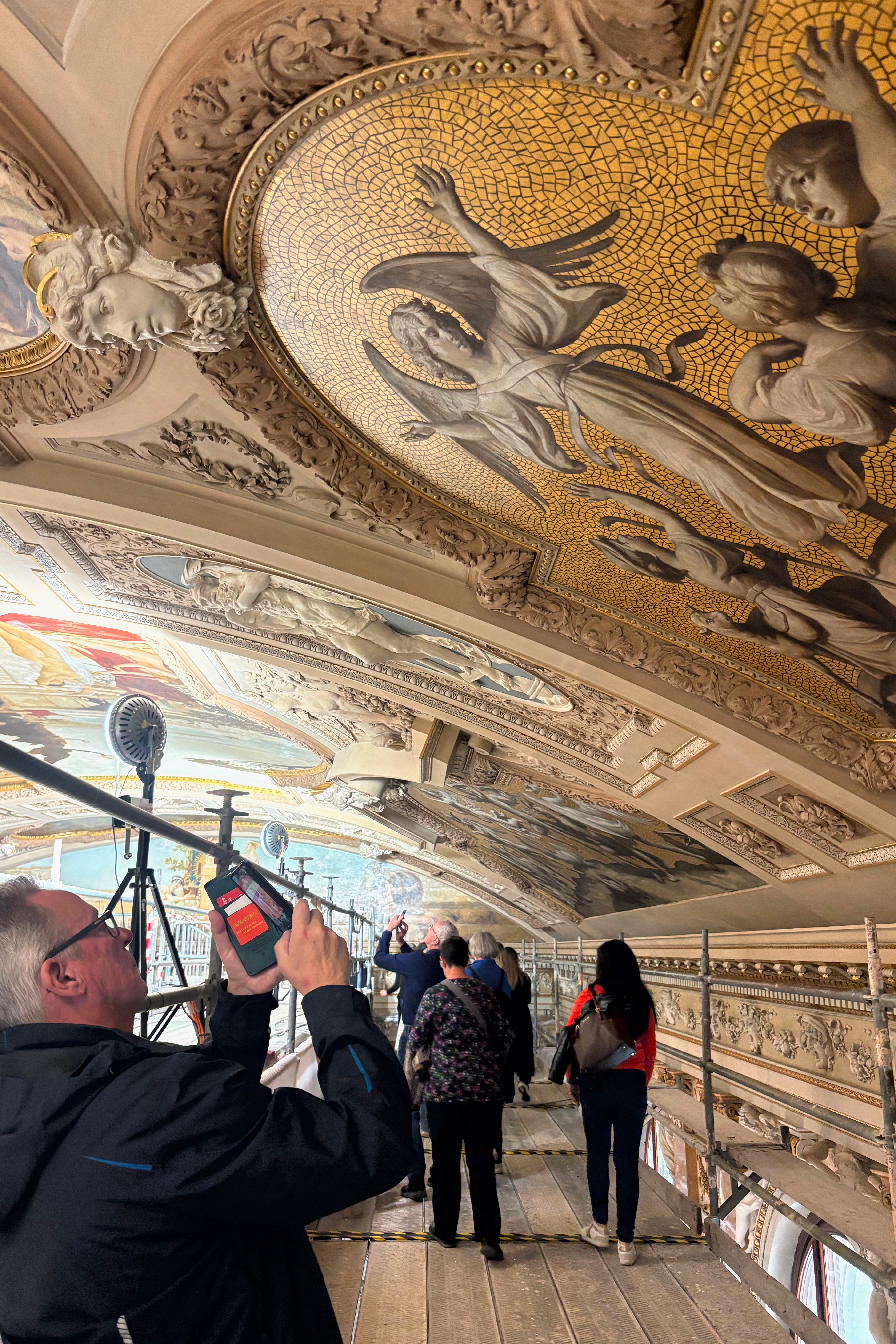 A man takes a picture with his mobile phone during a guided tour of the restoration of Gustav Klimt's ceiling paintings at the Burgtheater