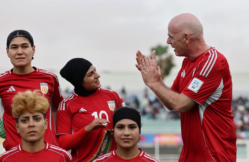 Gianni Infantino, president of Fifa, applauds as he poses for a photograph with players of Afghan Women's United prior to their match against Tunisia on 29 October 2025