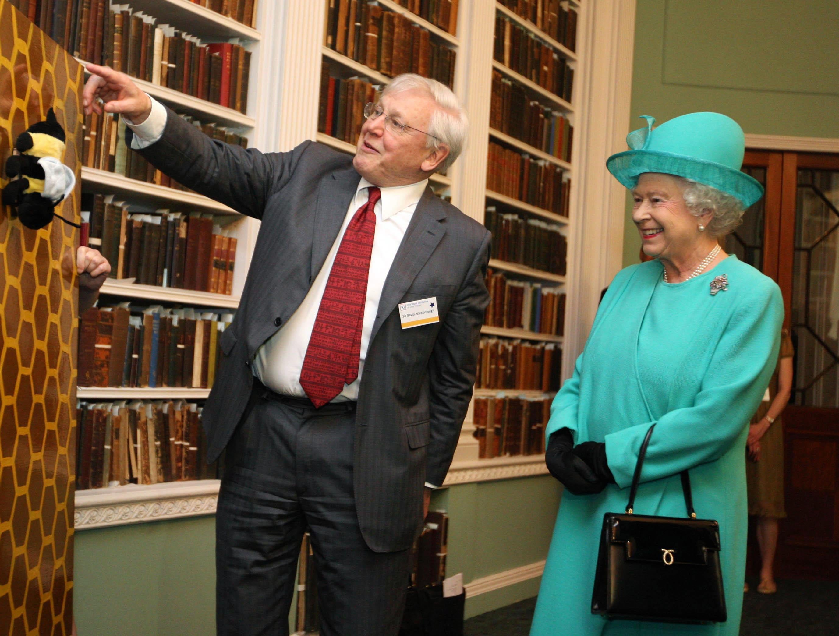 Rainha Elizabeth II sorrindo enquanto Sir David Attenborough dá um segmento de uma palestra de Natal na Royal Institution of Great Britain.