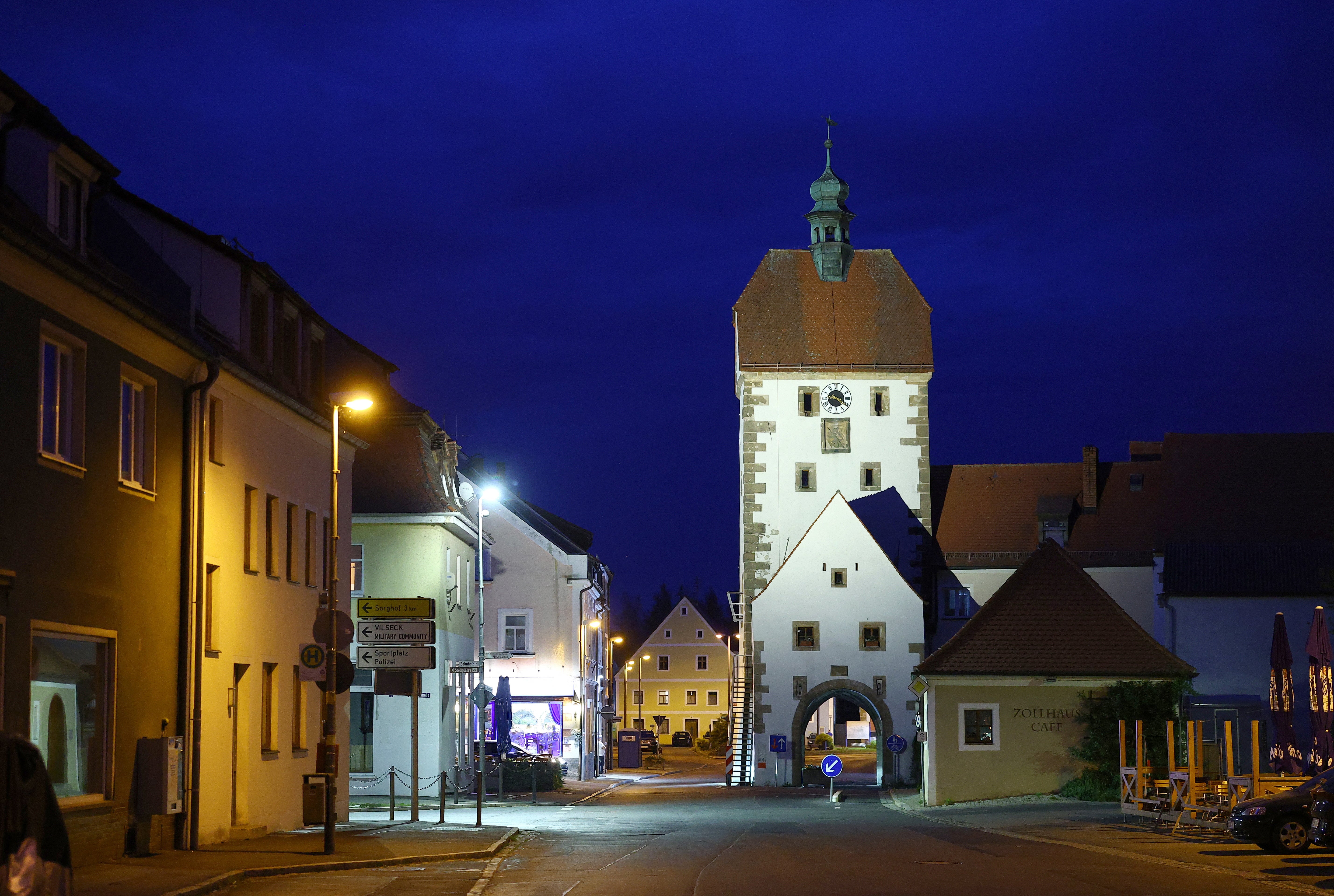 The gate tower of the ancient town wall is illuminated at dusk in Vilseck, Germany
