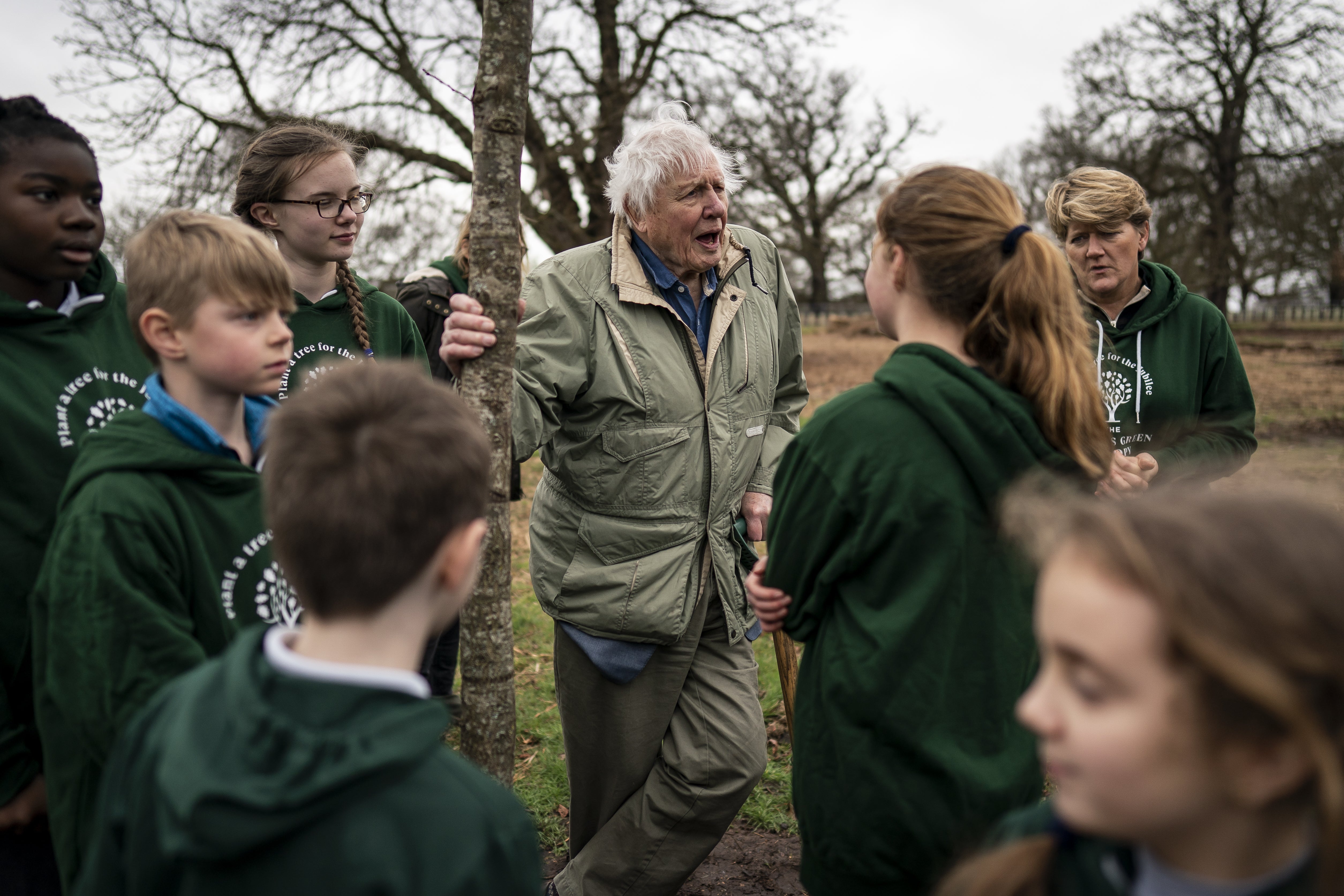 Sir David Attenborough com Clare Balding (atrás à direita) plantando uma árvore em homenagem à Rainha Elizabeth II.