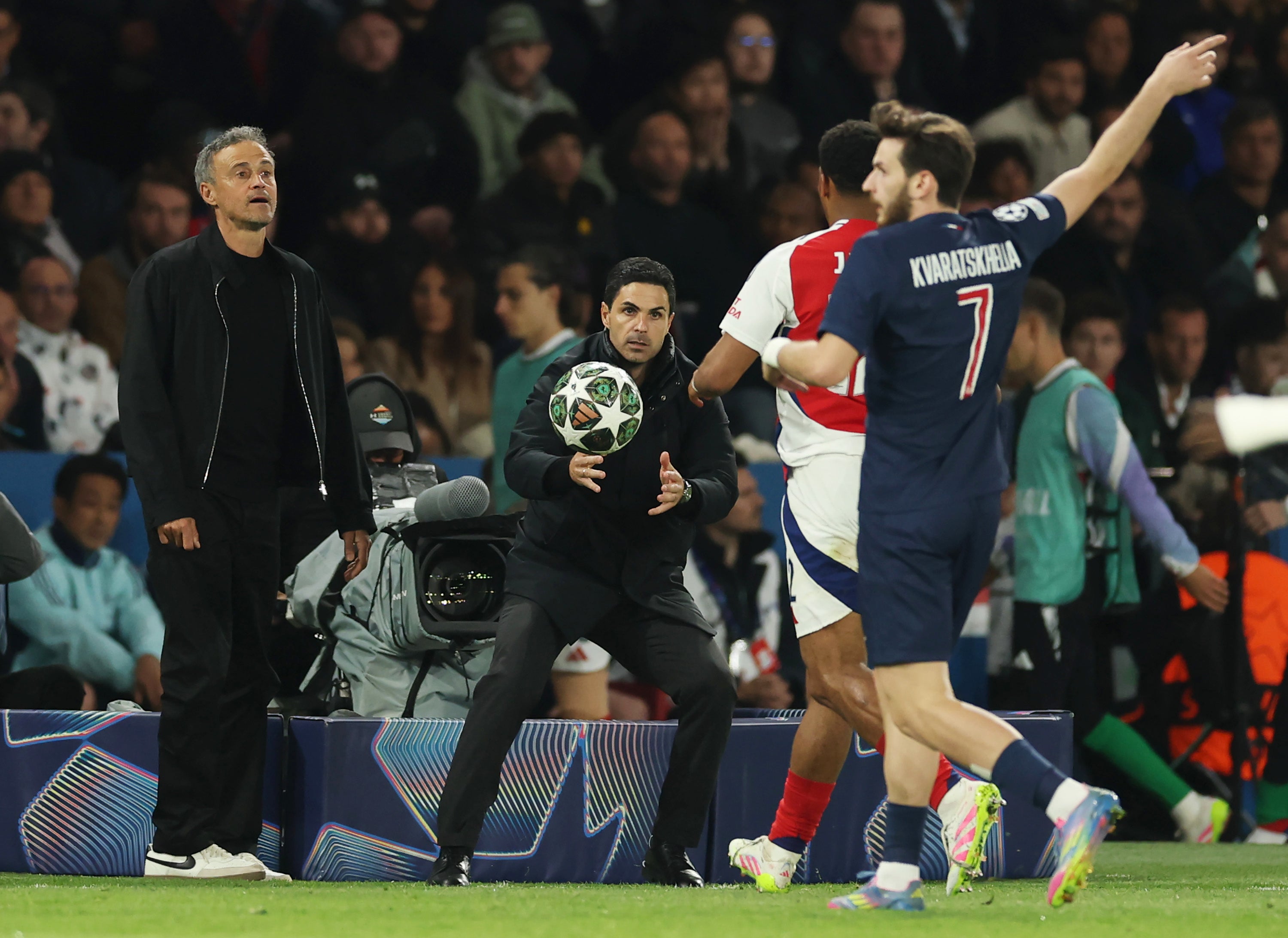 Mikel Arteta, Manager of Arsenal, catches the ball as Luis Enrique, Head Coach of Paris Saint-Germain