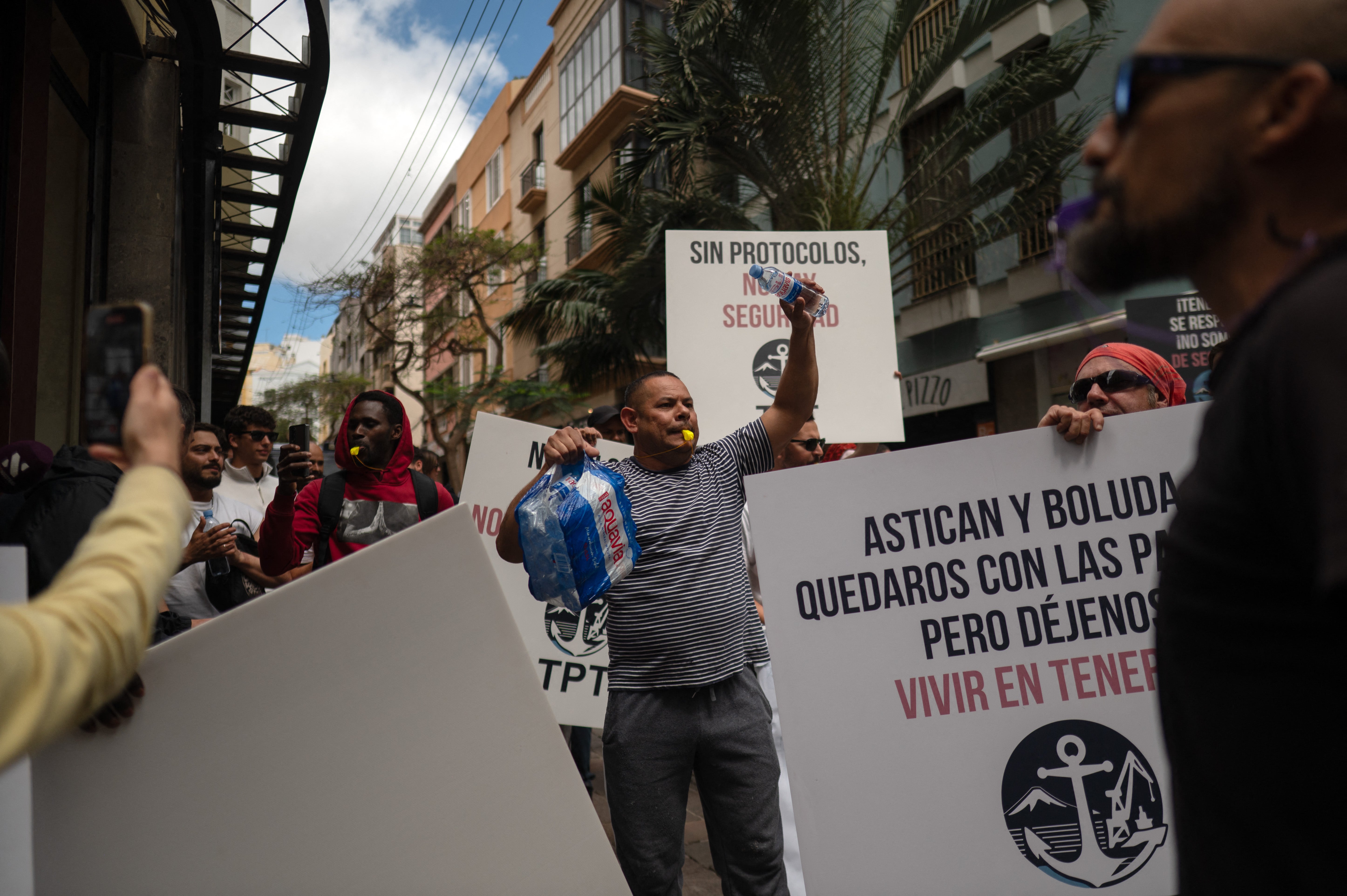 Dockers hold banners reading 'without protocol, no safety' as they protest against the arrival of a cruise ship affected by hantavirus
