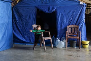 A child sits on a chair near a tent inside the Camille Chamoun Sports City Stadium, turned into a temporary shelter in Beirut, Lebanon, May 8