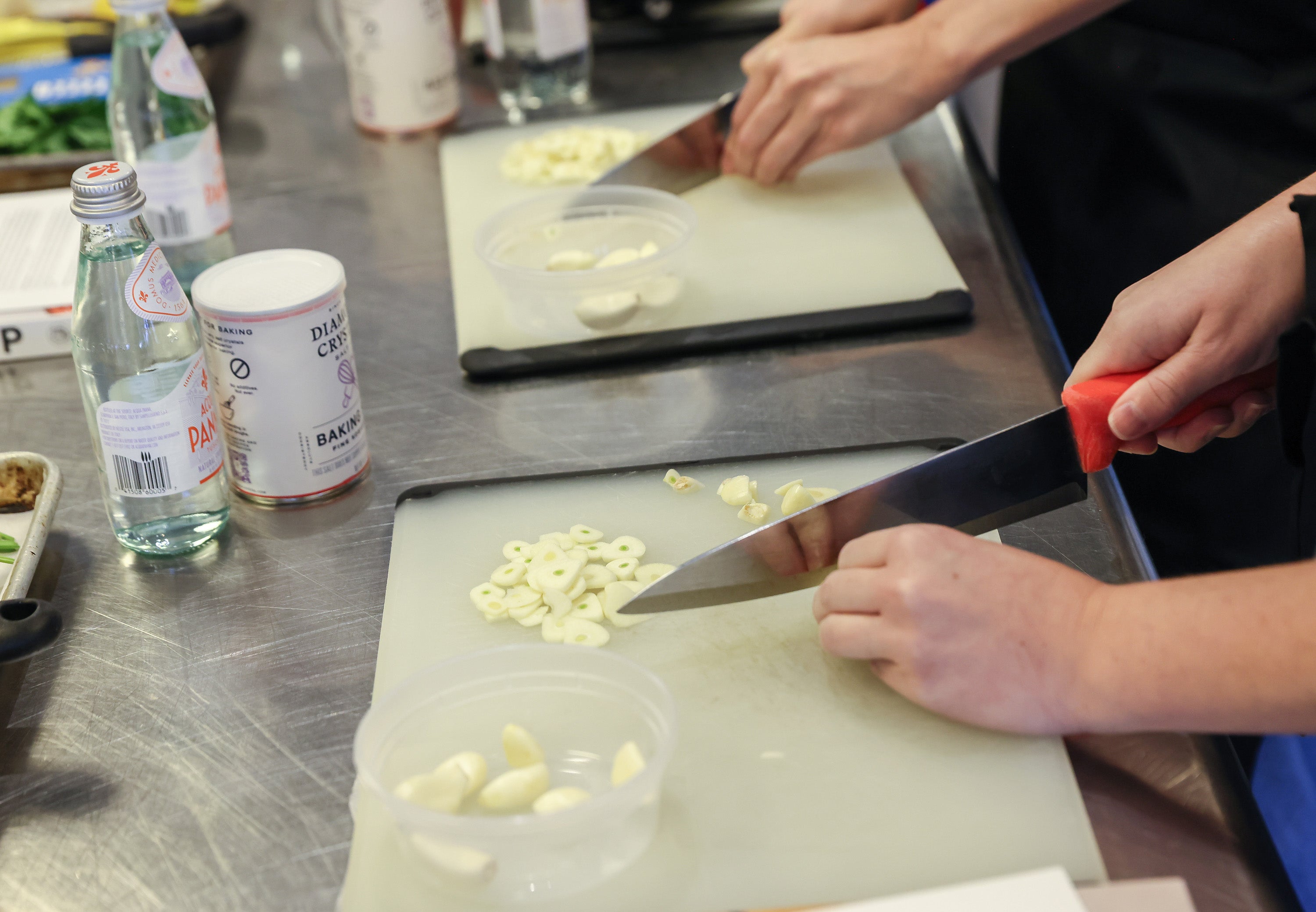 Students chop garlic as they prepare a pasta dish