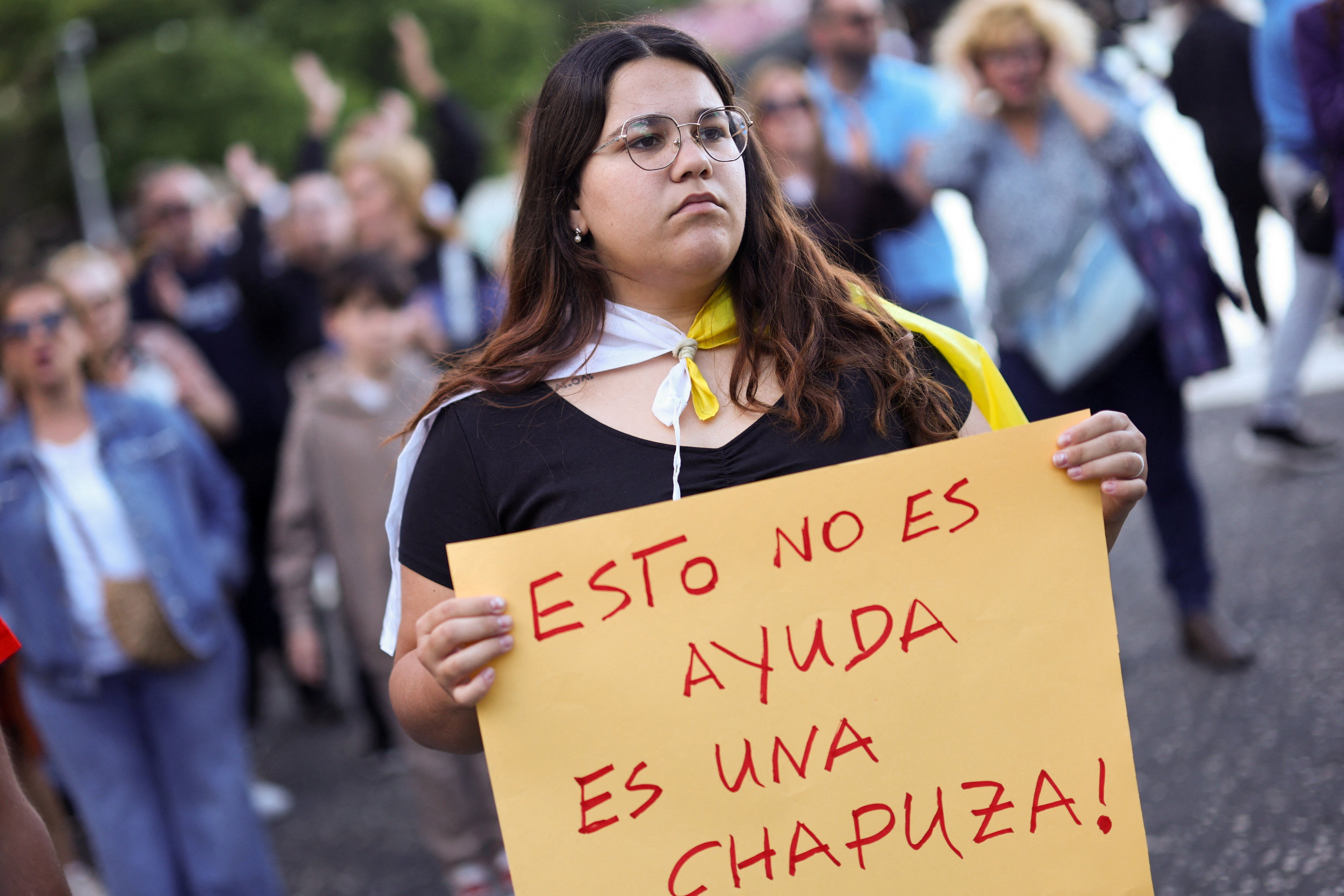 A demonstrator holds a placard reading: ‘This not help. This is a botched job.’