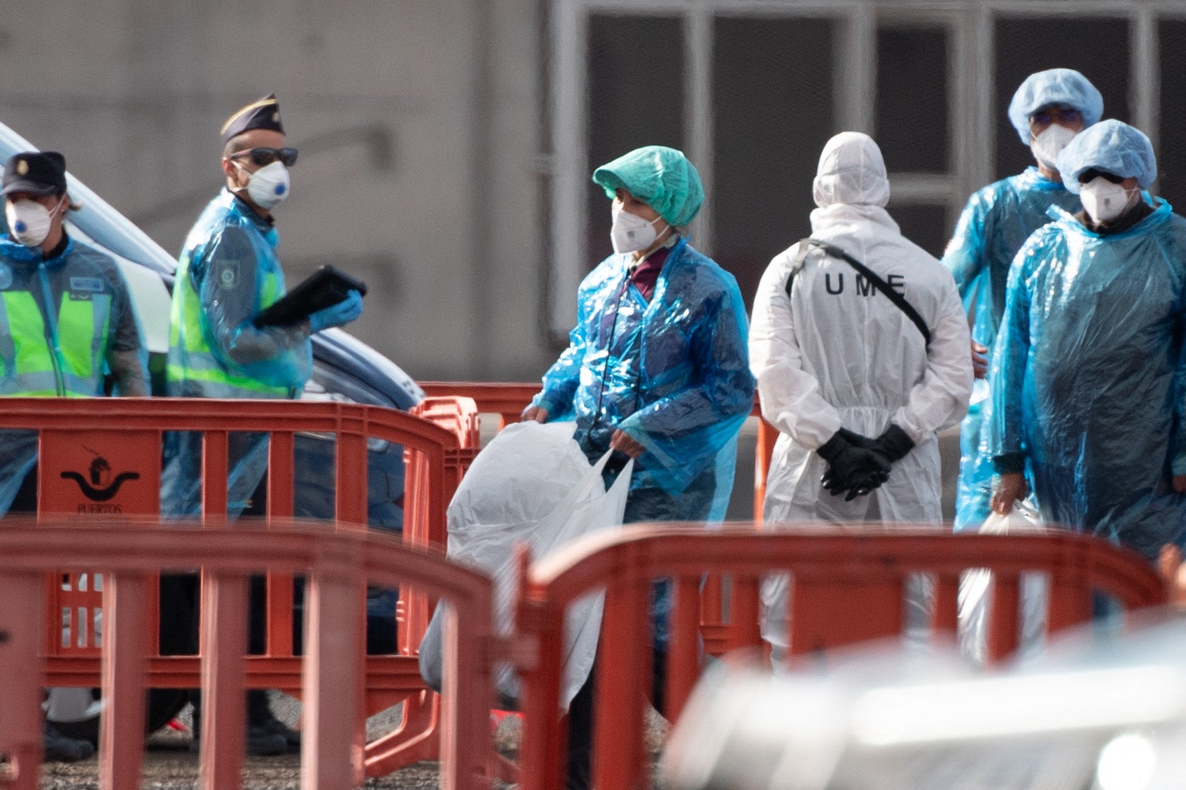 Passengers wearing blue protective suits board a military bus
