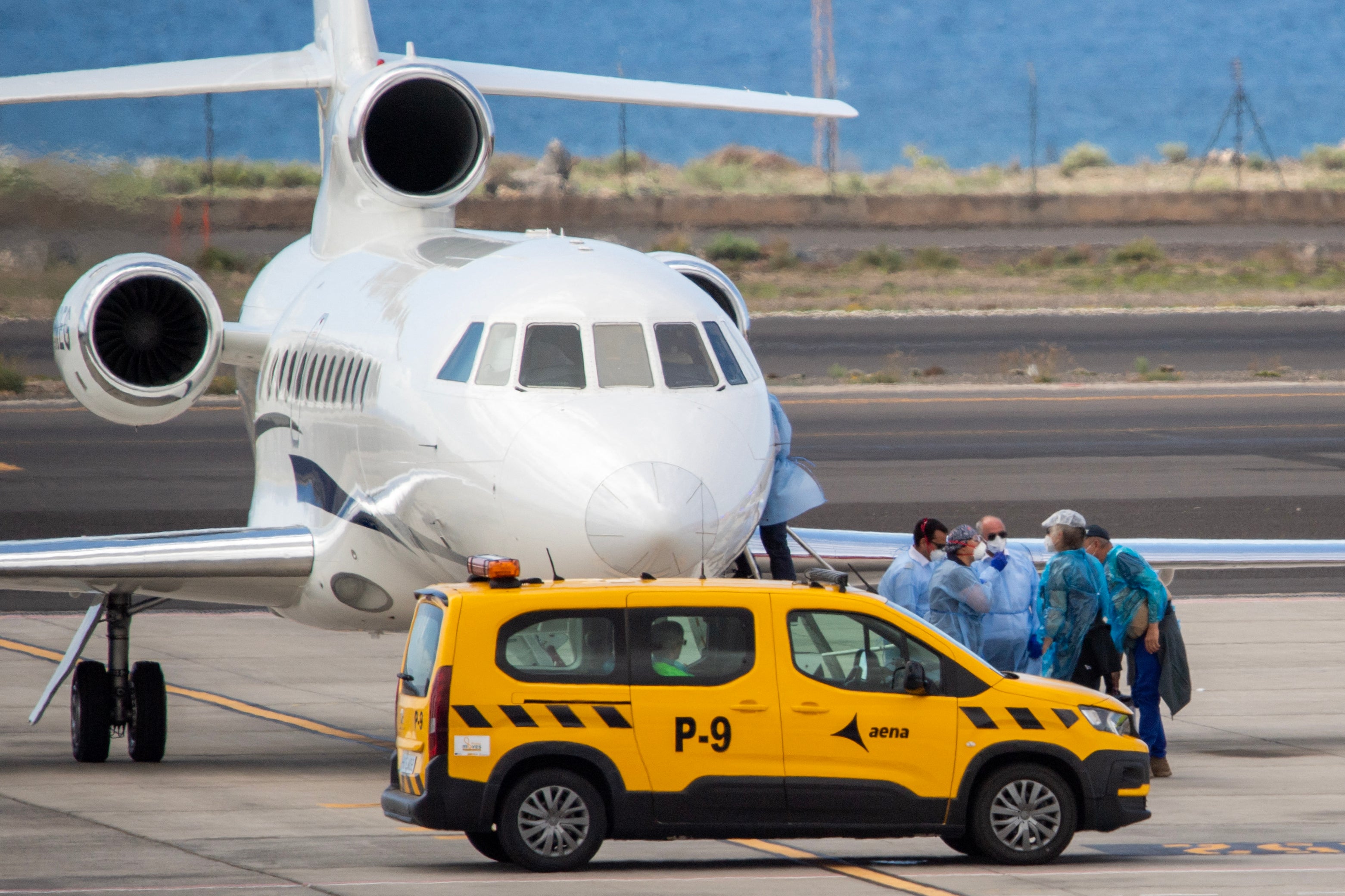 Passengers wearing blue protective suits board a French government plane after being evacuated from the hantavirus-stricken cruise ship