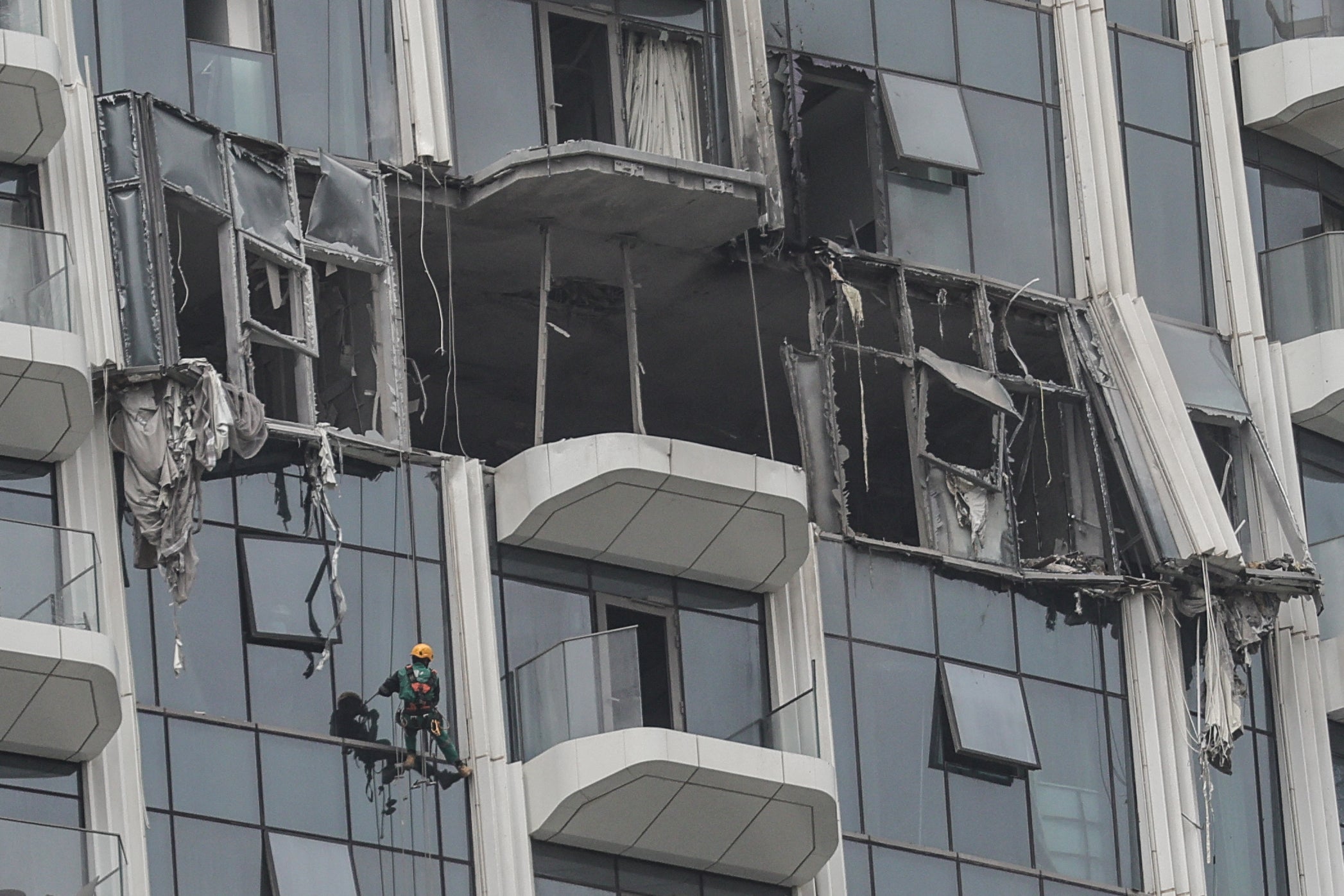 A steeplejack assesses the damage after a drone strike in Dubai's Creek Harbour