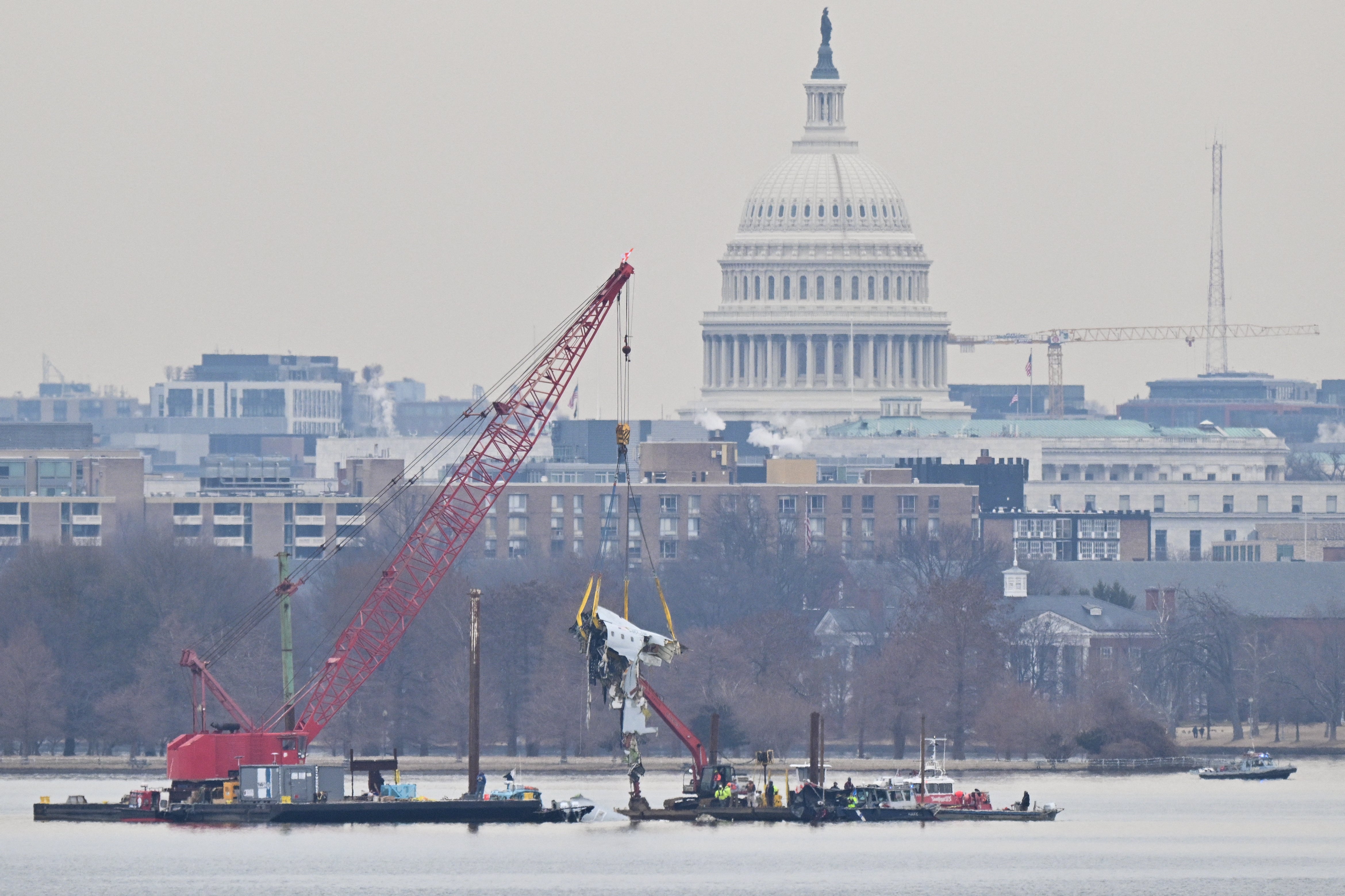 The US Capitol is seen in the background as a crane removes wreckage from the Potomac River in Washington, on Feb. 3, 2025, following the deadly midair collision of a passenger plane and a military helicopter