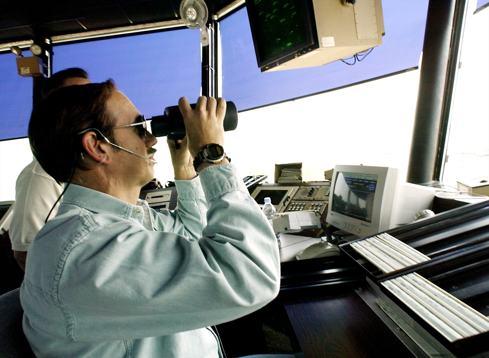 An air traffic controller uses binoculars to scan the sky at Dulles Airport in Virginia on Sept. 3, 2002. The Federal Aviation Administration is grappling with a shortage of controllers blamed on reduced hiring and attrition during the 2010s and the COVID-19 pandemic