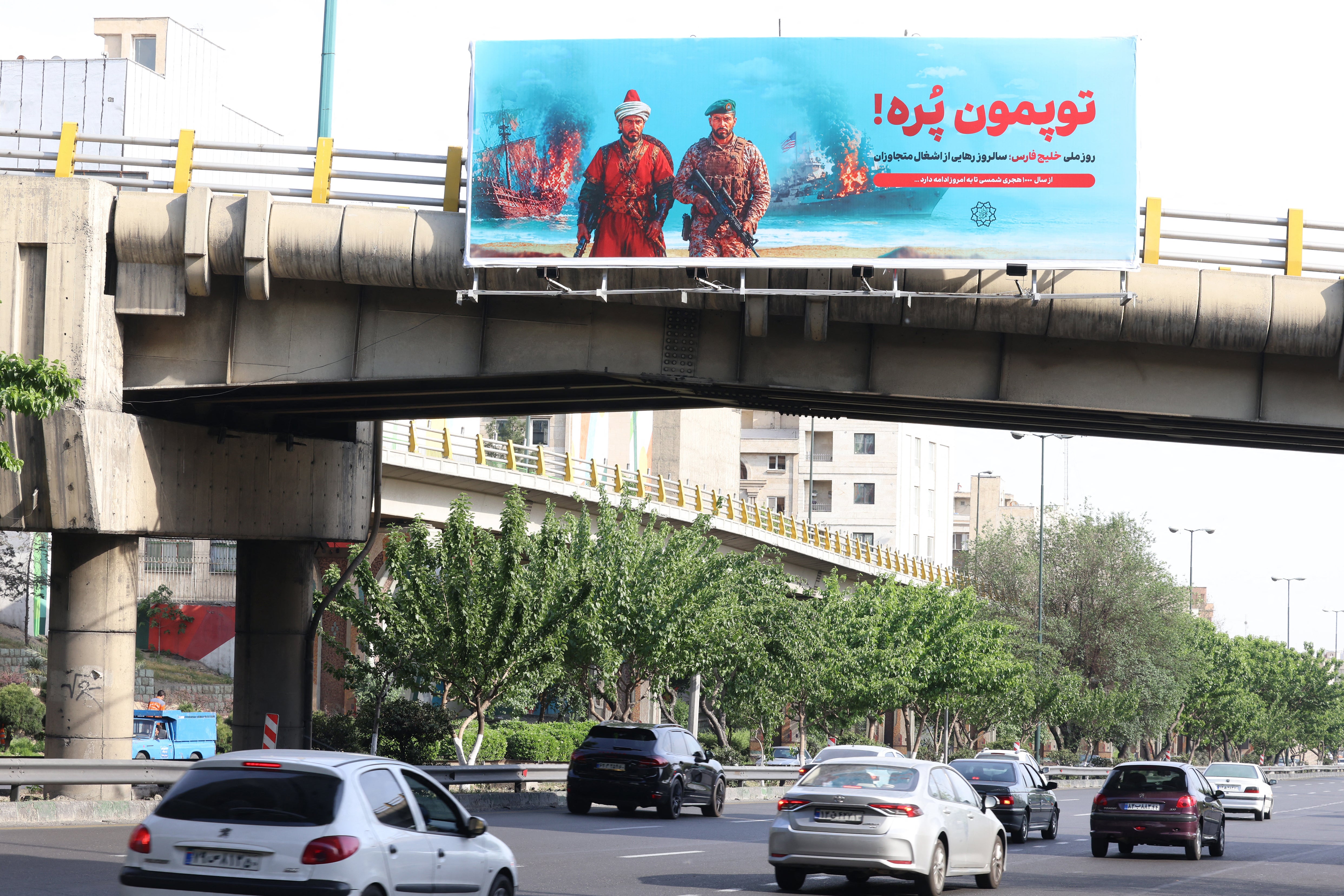 A large anti-American banner that reads in Persian, "Our cannons are full", referring to the Strait of Hormuz, is placed across a bridge that spans a highway in Tehran