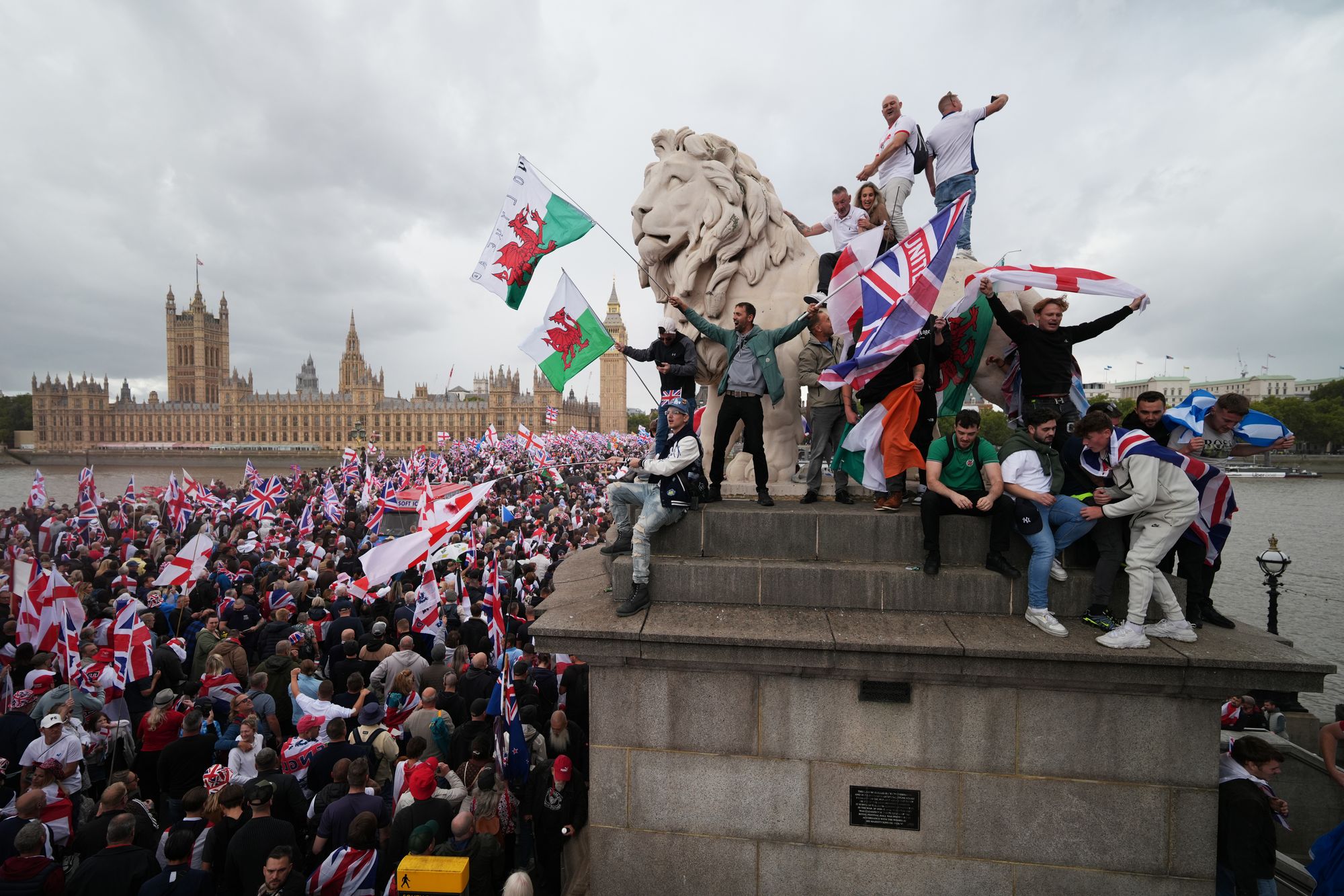 Protesters wave Union Jack and St George’s England flags during the ‘Unite the Kingdom’ rally on Westminster Bridge by the Houses of Parliament on 13 September 2025 in London, England