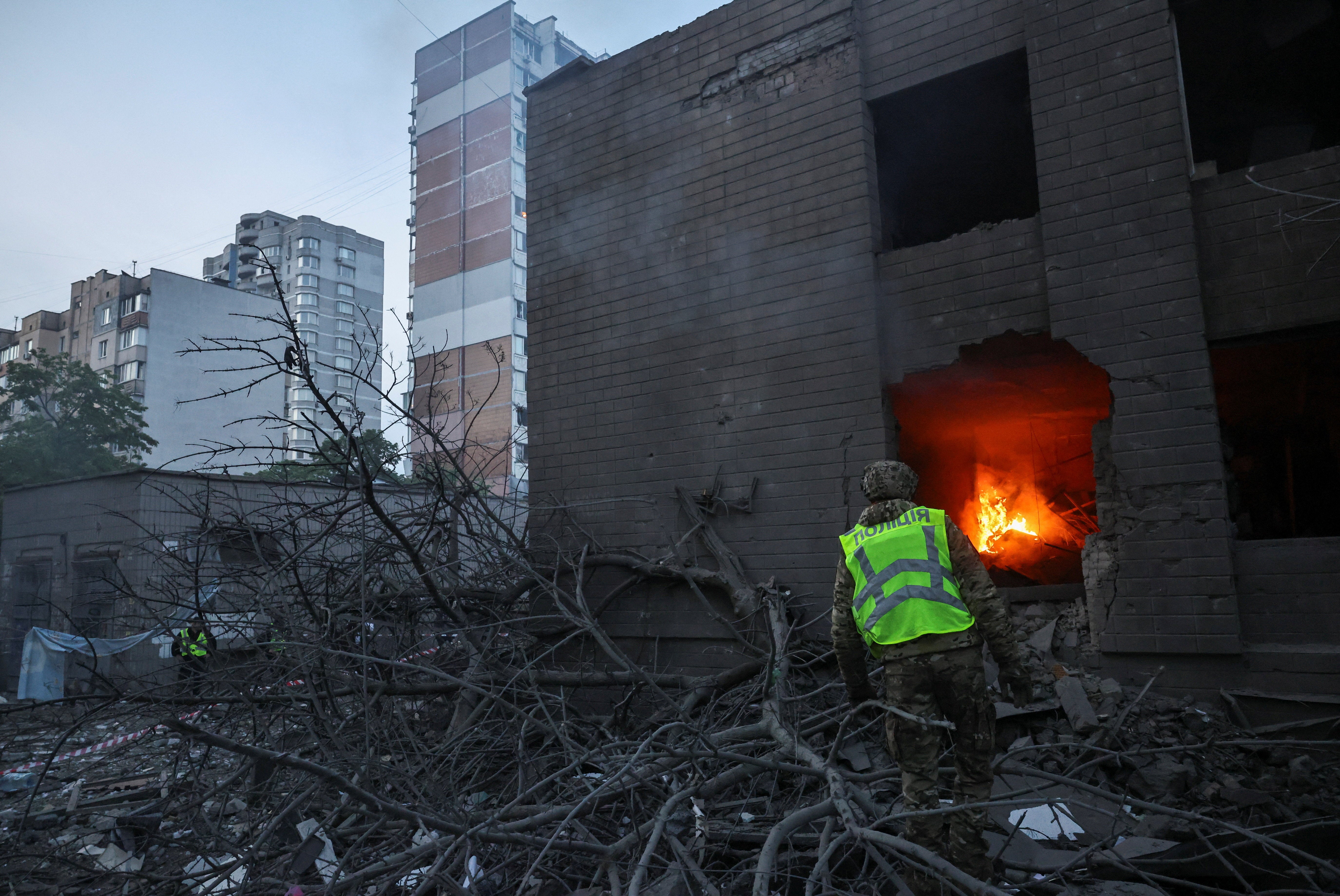 Rescuer looks at a fire in a building damaged during Russian missile and drone strikes in Kyiv