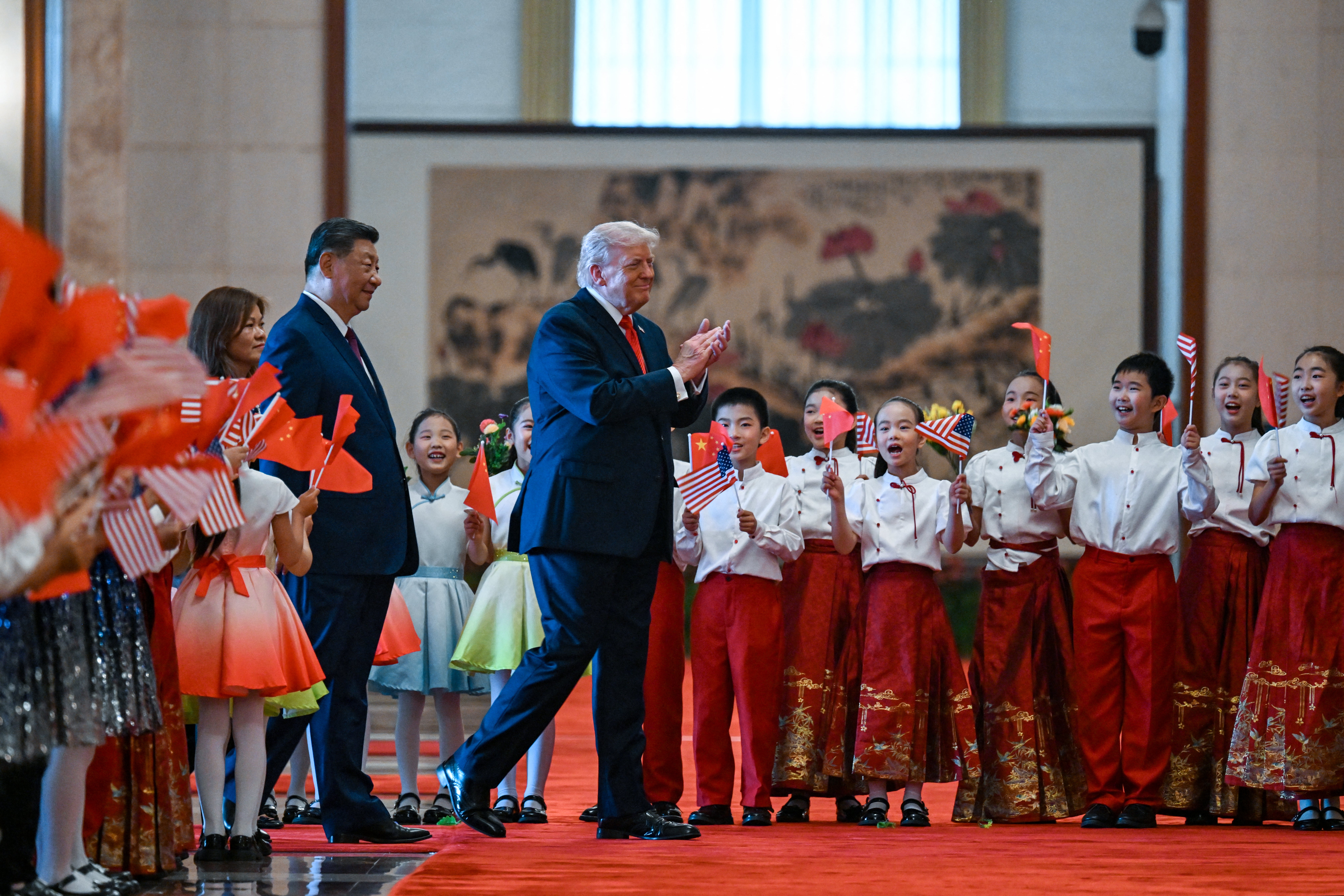 US President Donald Trump (R) and China's President Xi Jinping (L) greet children waving Chinese and US national flags and flowers during a welcome ceremony at the Great Hall of the People