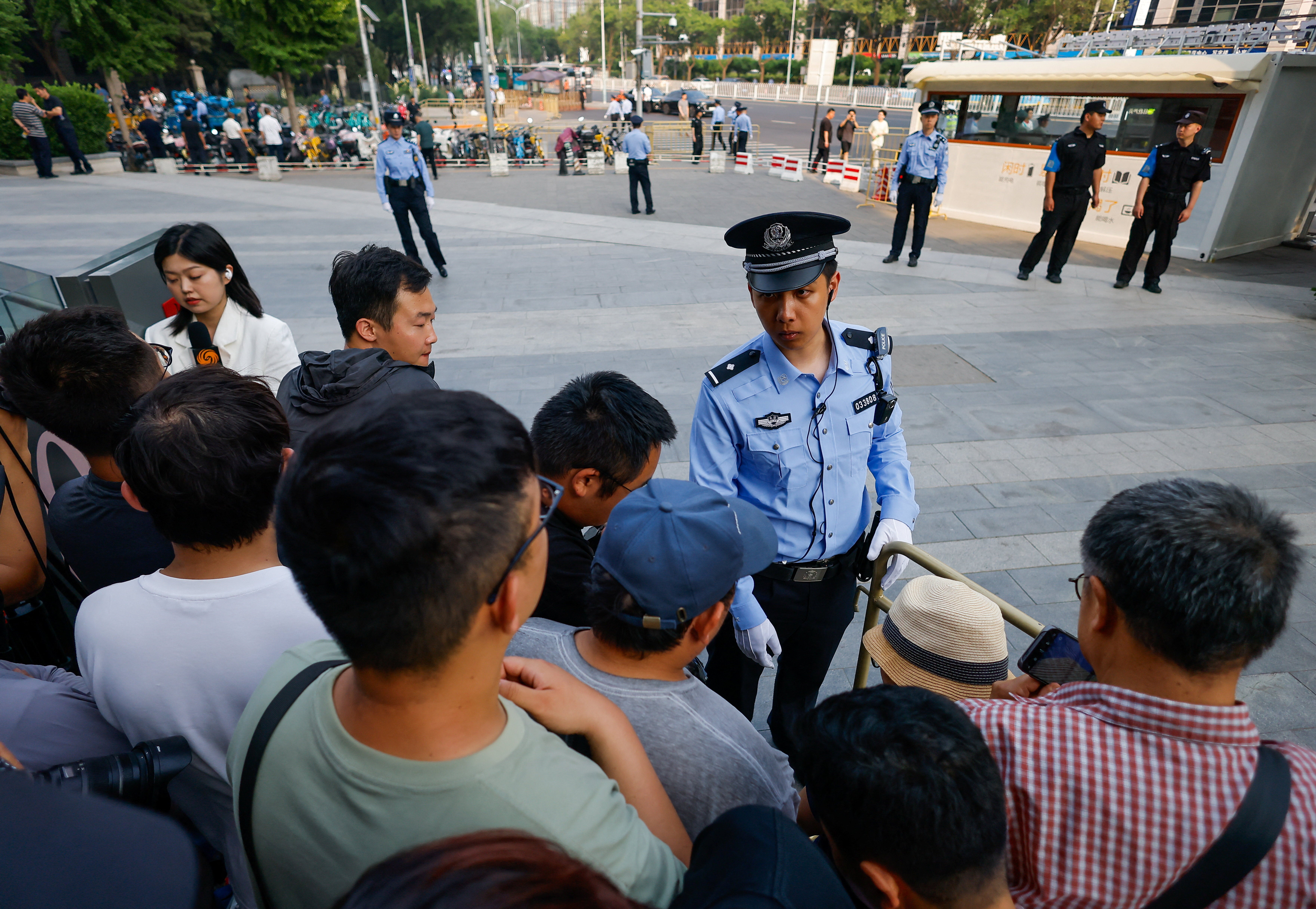 People line up along a street as they wait for a motorcade carrying US president Donald Trump to pass by during his visit to China in Beijing on 14 May 2026