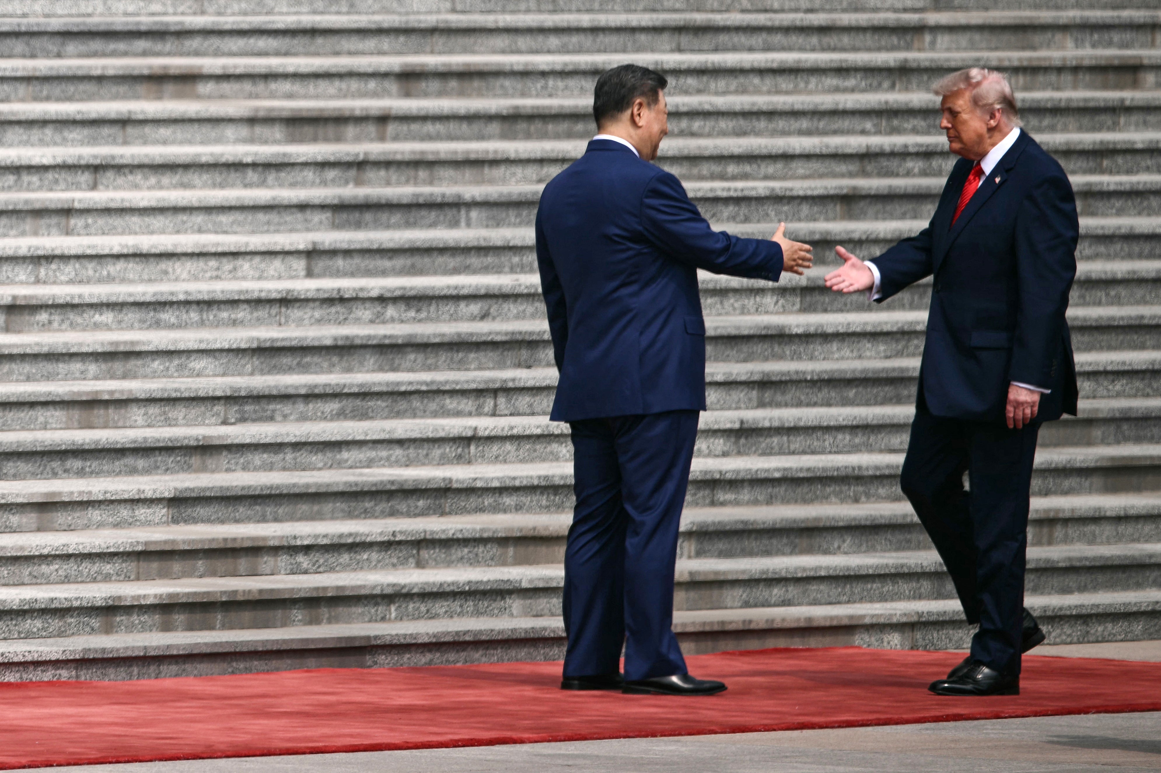 President Donald Trump initiates a handshake with Chinese Premier Xi Jinping in front of the Great Hall of the People in Beijing Wednesday