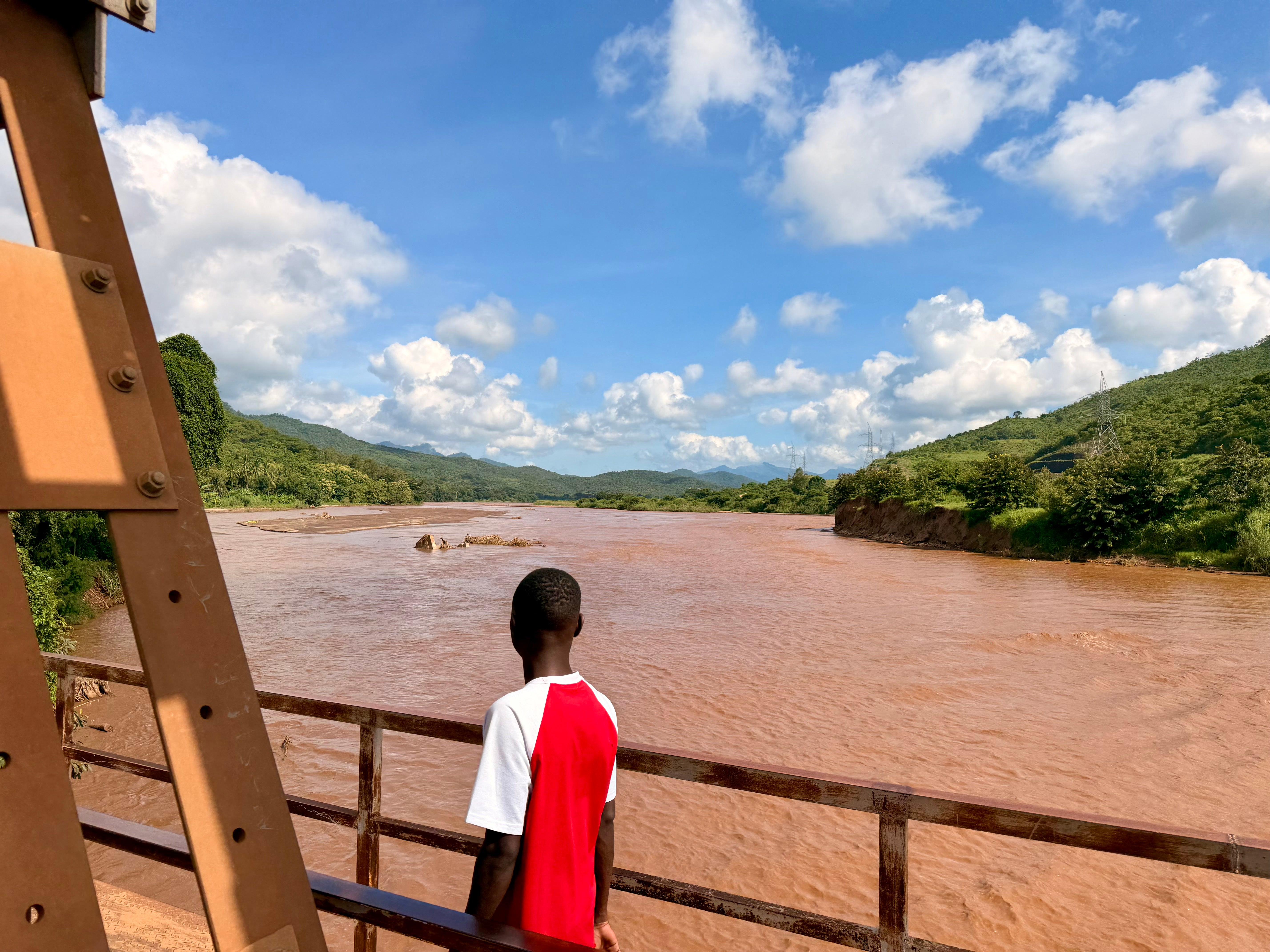 A man crosses the main road bridge across Mkondoa River, the main one in Ulaya, where broken banks and collapsed trees show the damage extreme rainfall has recently caused