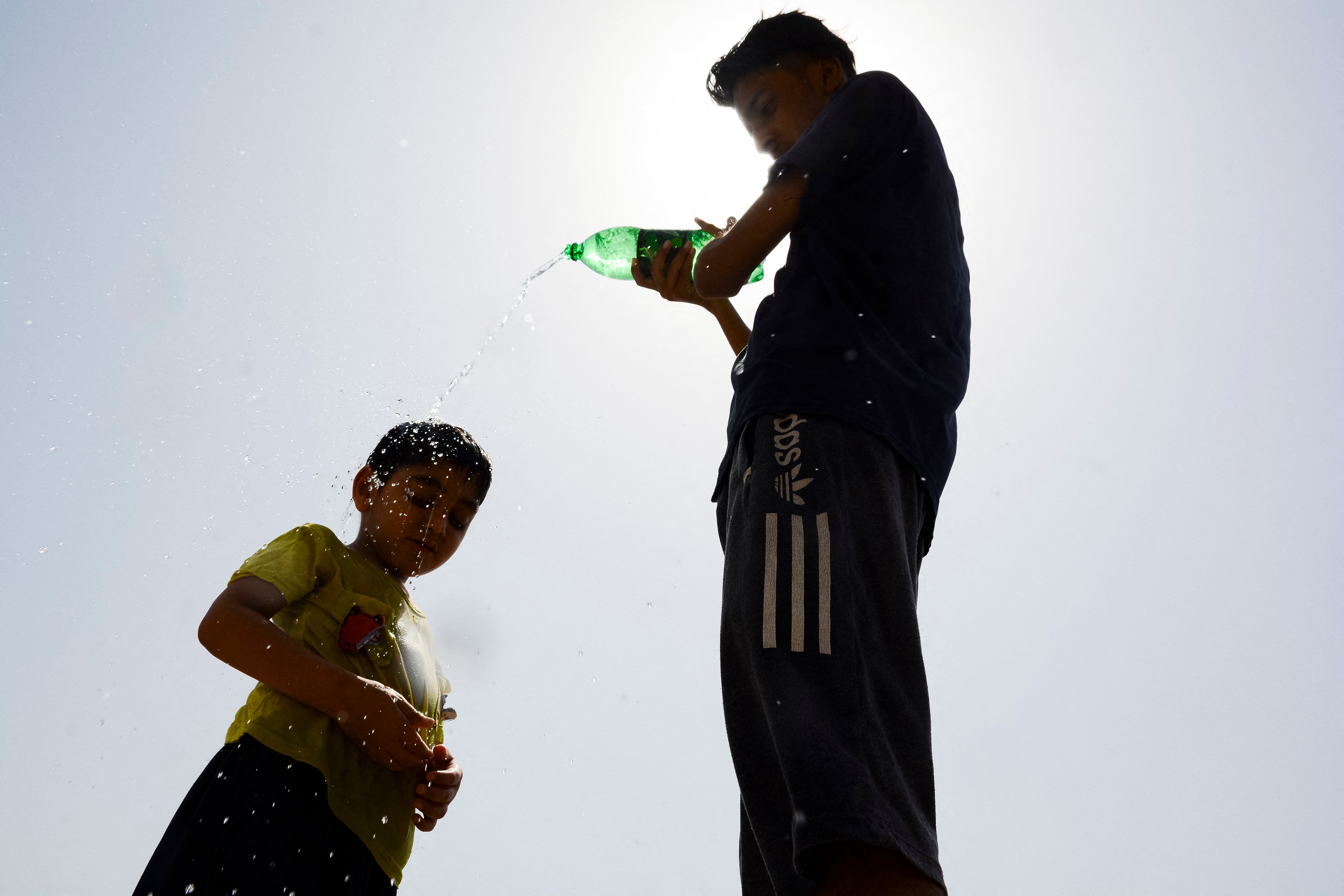 Children cool off with water during a scorching summer afternoon in Lahore, Pakistan,