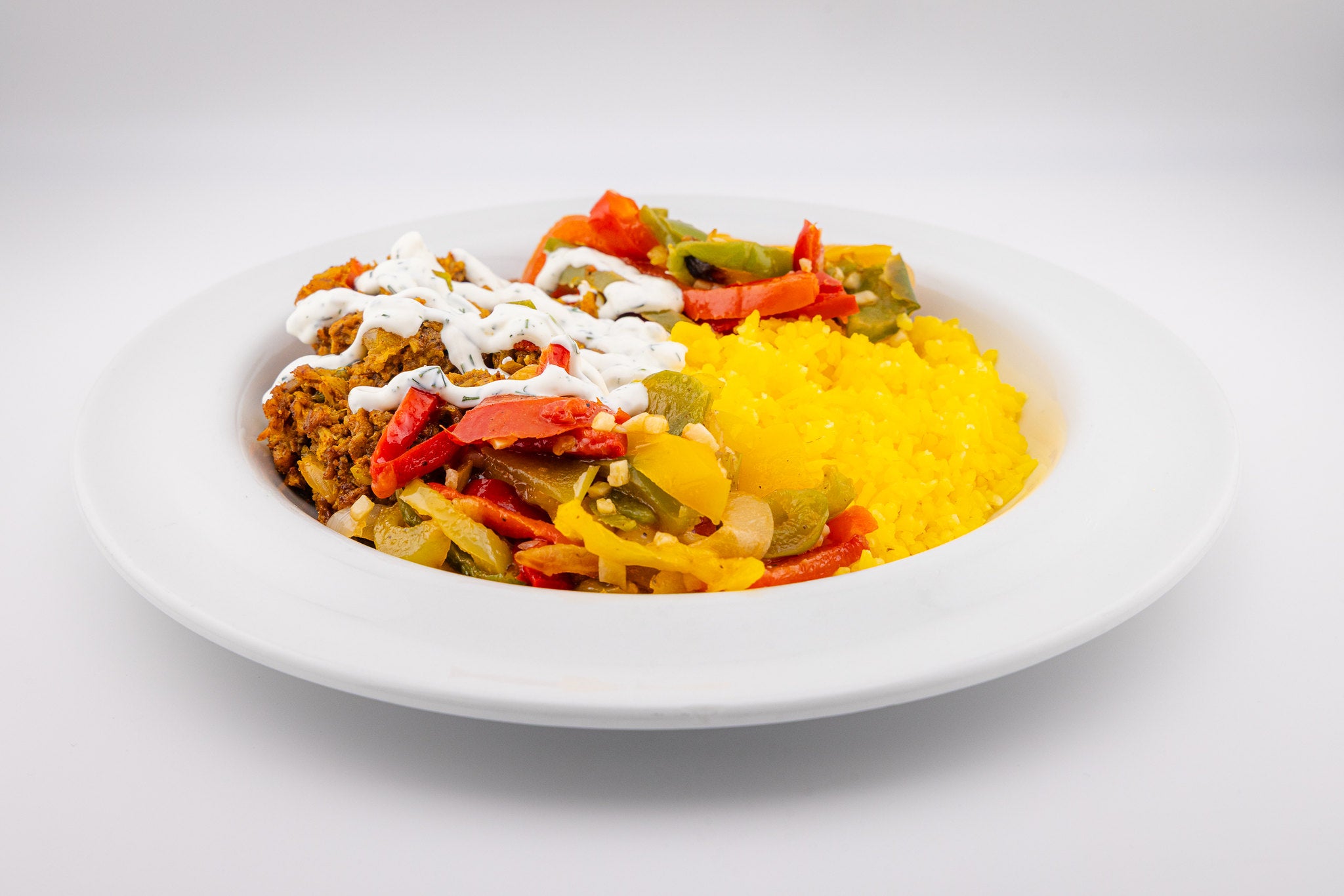 This hospital dish is entirely vegan — spice-rubbed shawarma mushrooms over golden rice with plant-based tzatziki and savory sautéed peppers