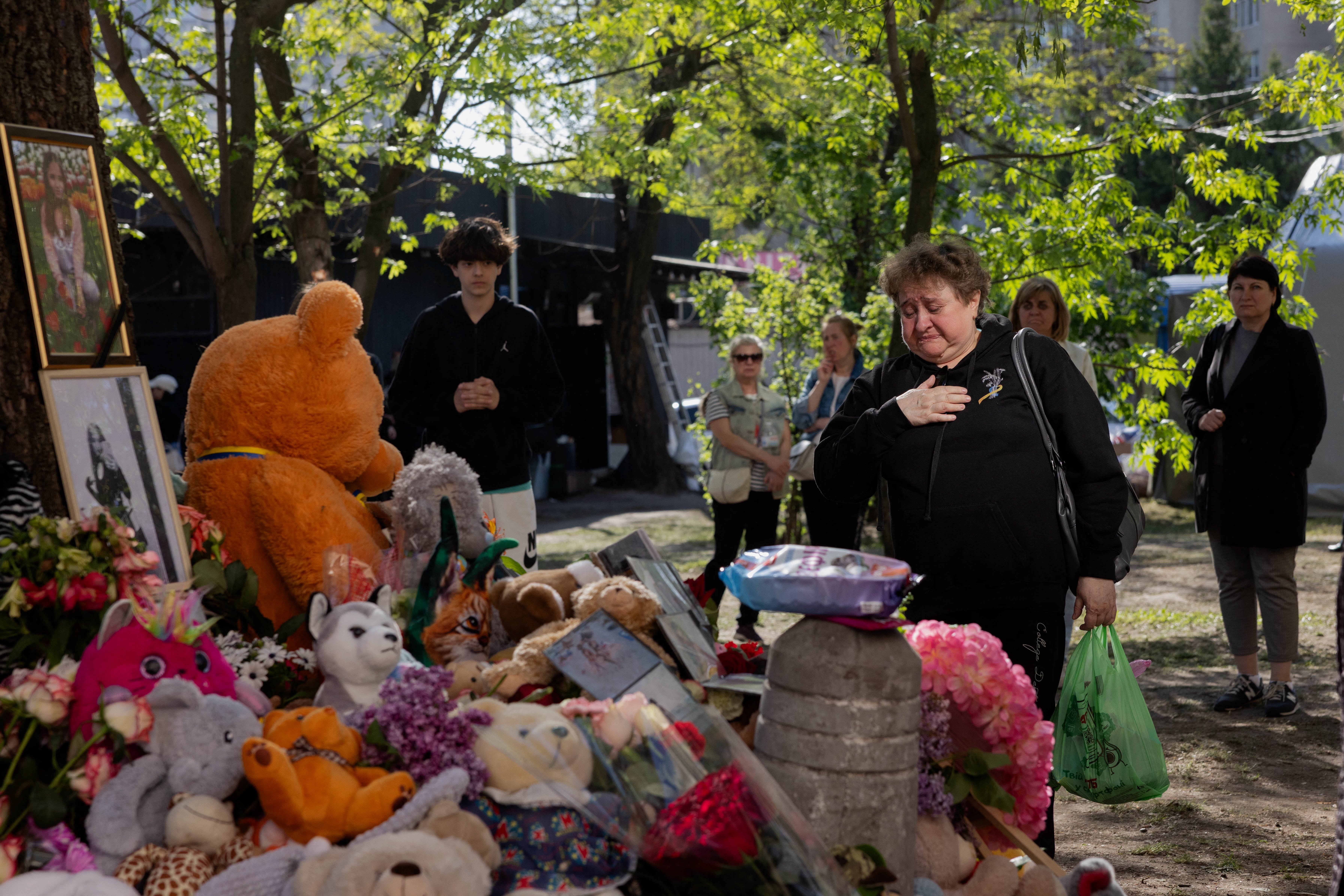 Local residents stand in front of a makeshift memorial near a partially destroyed residential building in Kyiv