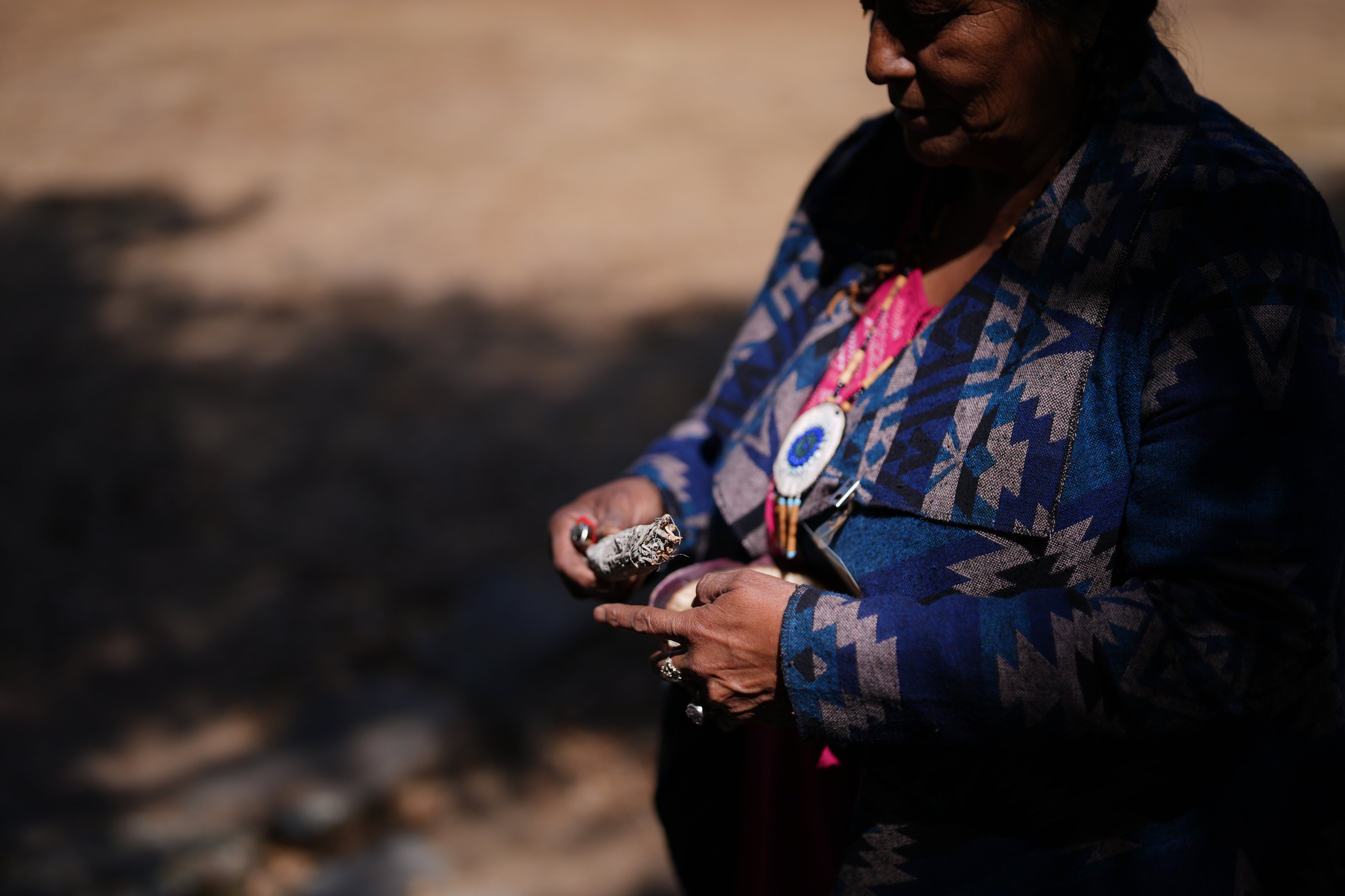 Norma Meza Calles, a Kumeyaay Nation leader, lights a bundle of white sage as she talks of the sacred importance of nearby Kuuchamaa Mountain