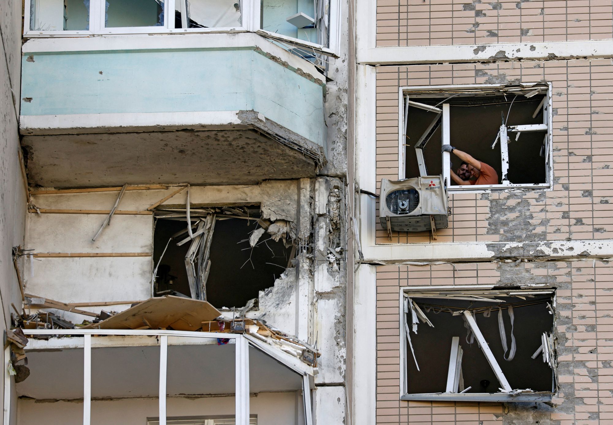 Residents clear broken windows in a damaged apartment building following a Ukrainian drone attack in the course of Russia-Ukraine