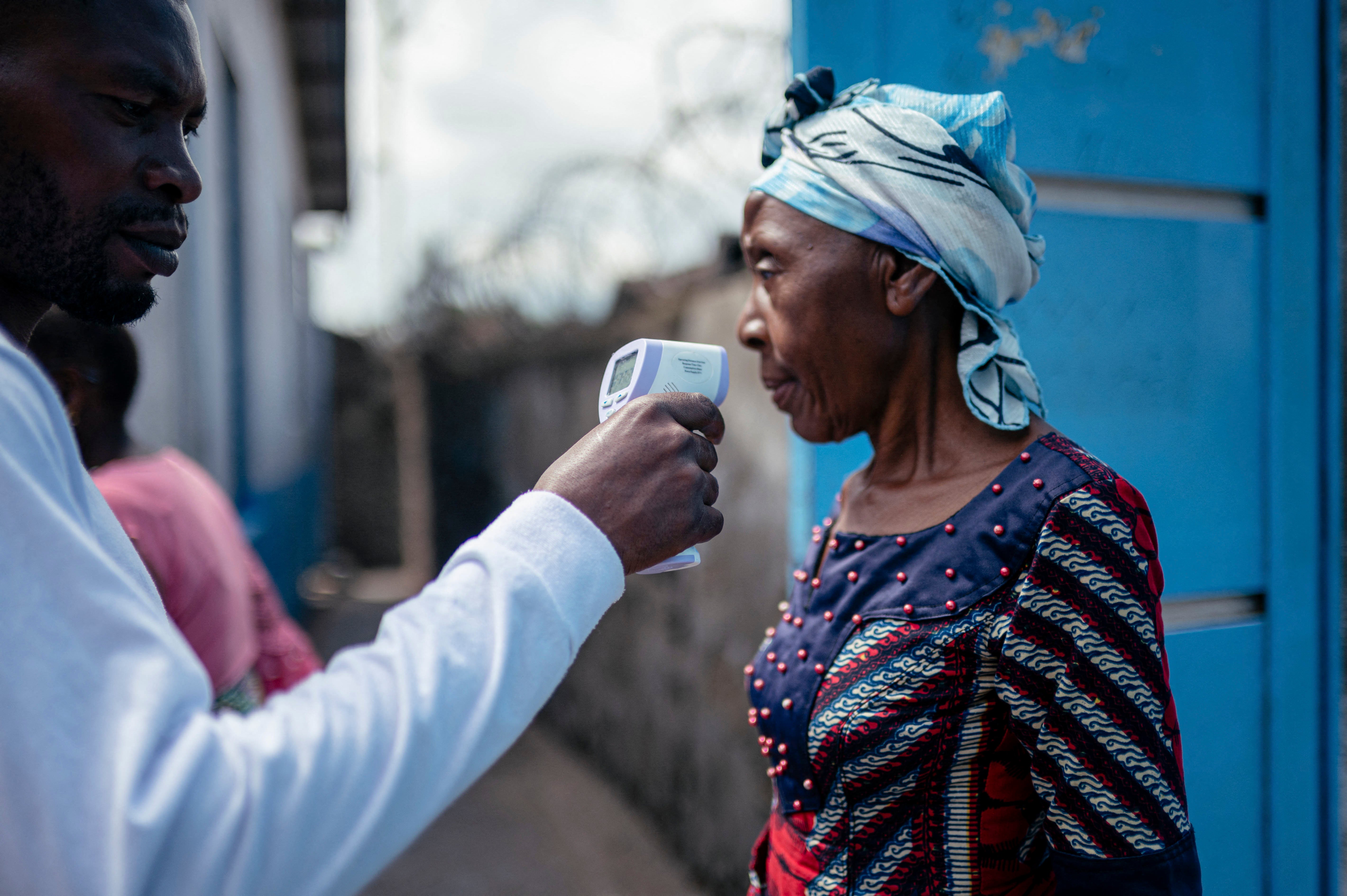 A staff member of the CBCA Virunga Hospital checks a visitor's temperature using a a contactless infrared thermometer, before allowing her access to the hospital in Goma on May 17