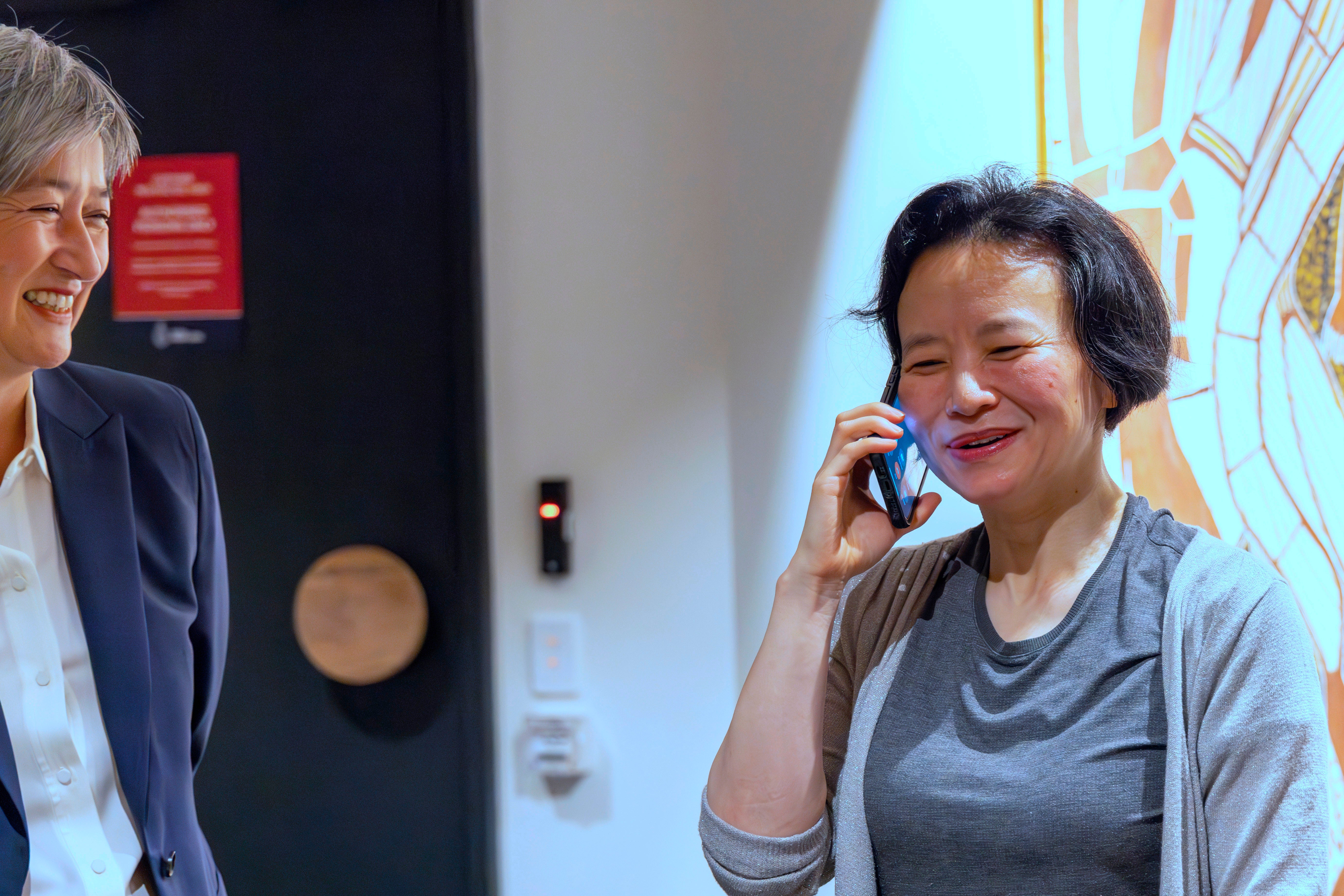 Cheng Lei, right, talks on the phone as Australia's Minister for Foreign Affairs, Penny Wong