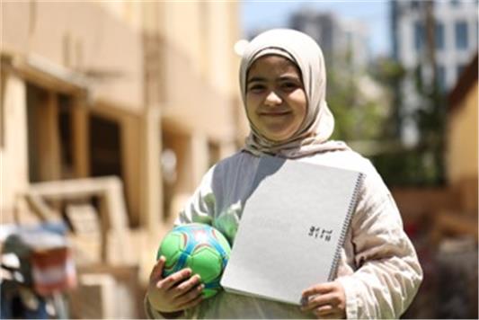 Tala, 10, brought her notebook so she could continue her studies in a displacement camp