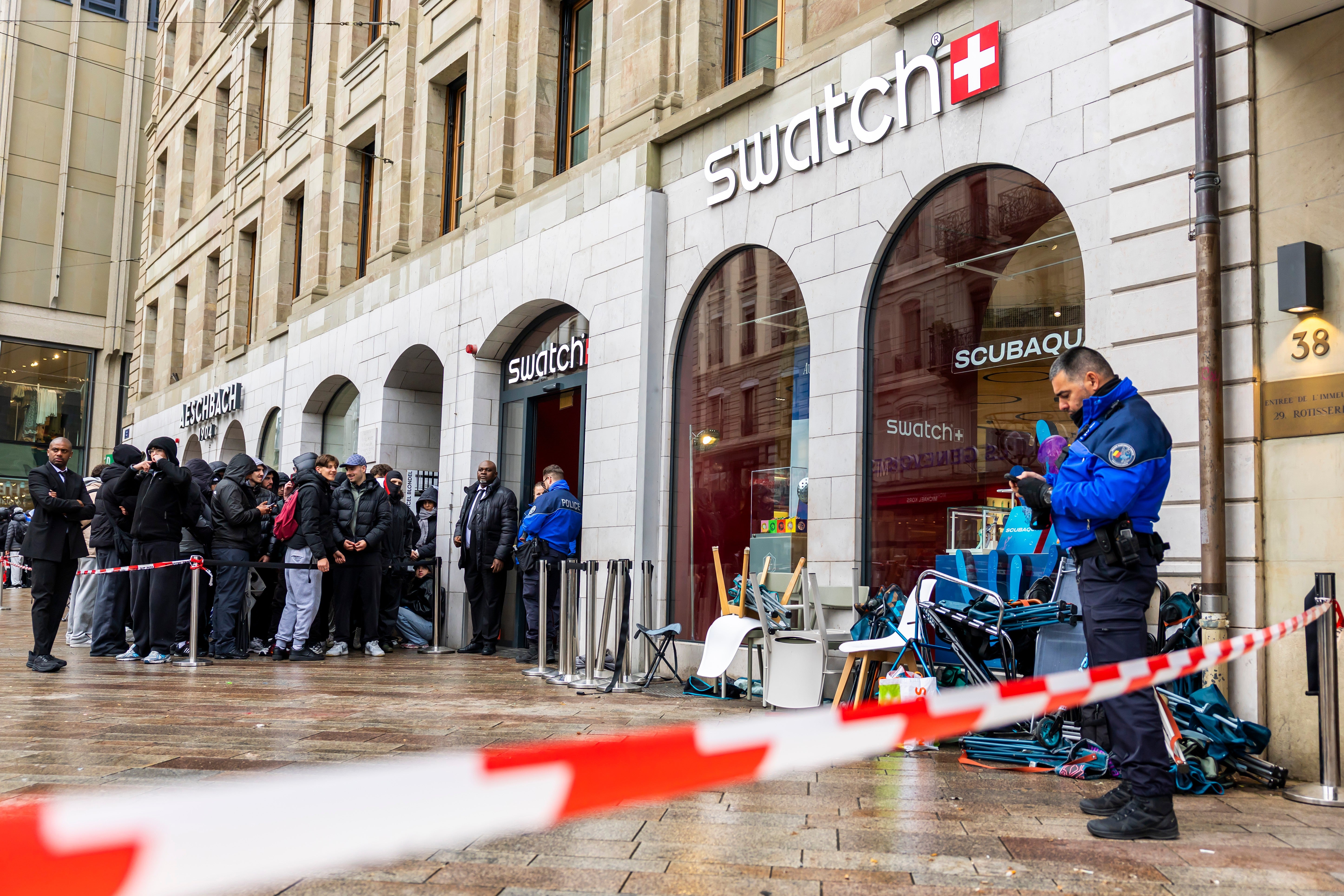 Swiss police officers secure the area where customers queue to buy the new Royal Pop watch by Swatch