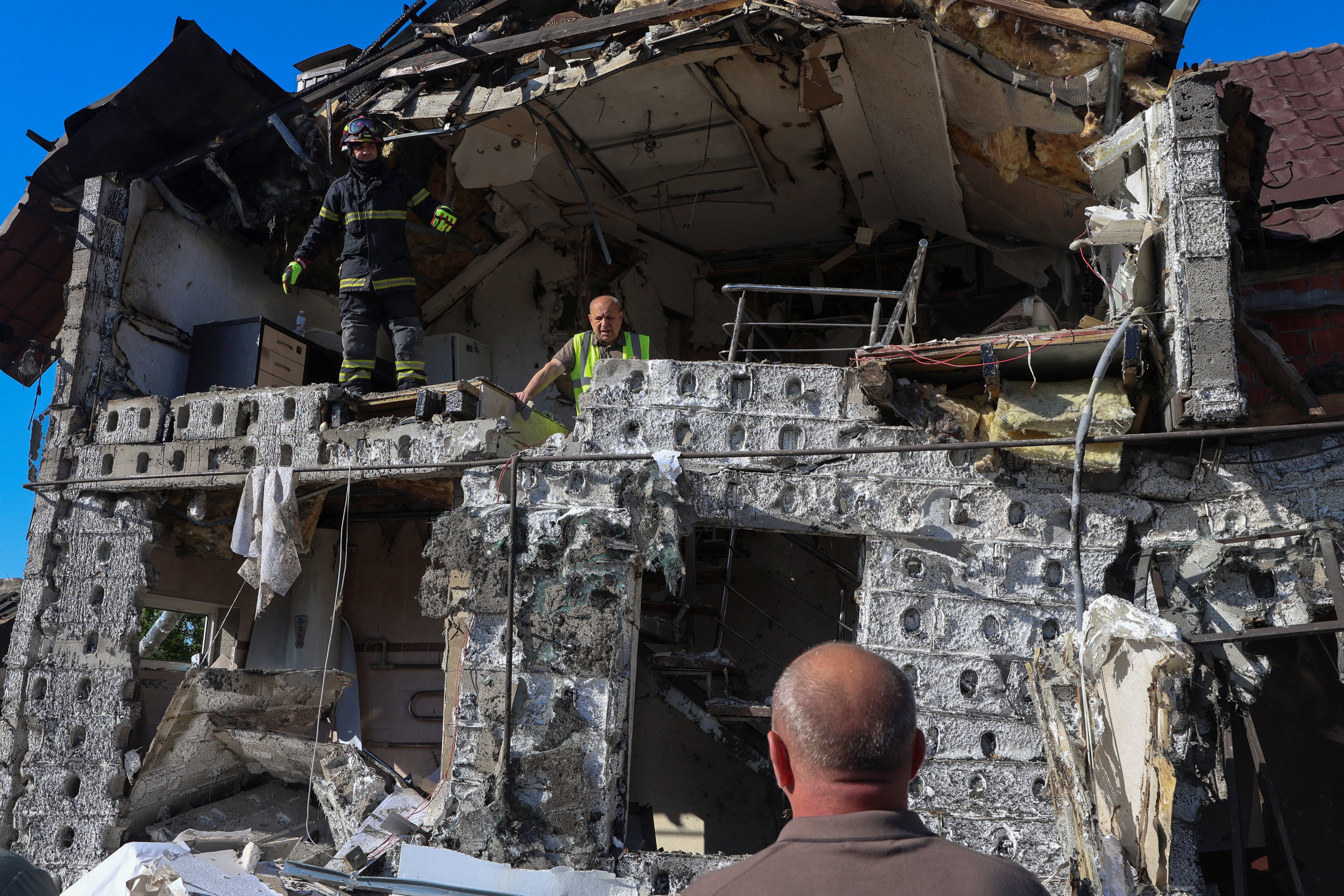 Residents and a rescuer inspect a house hit by a Russian drone strike in the morning in Kharkiv