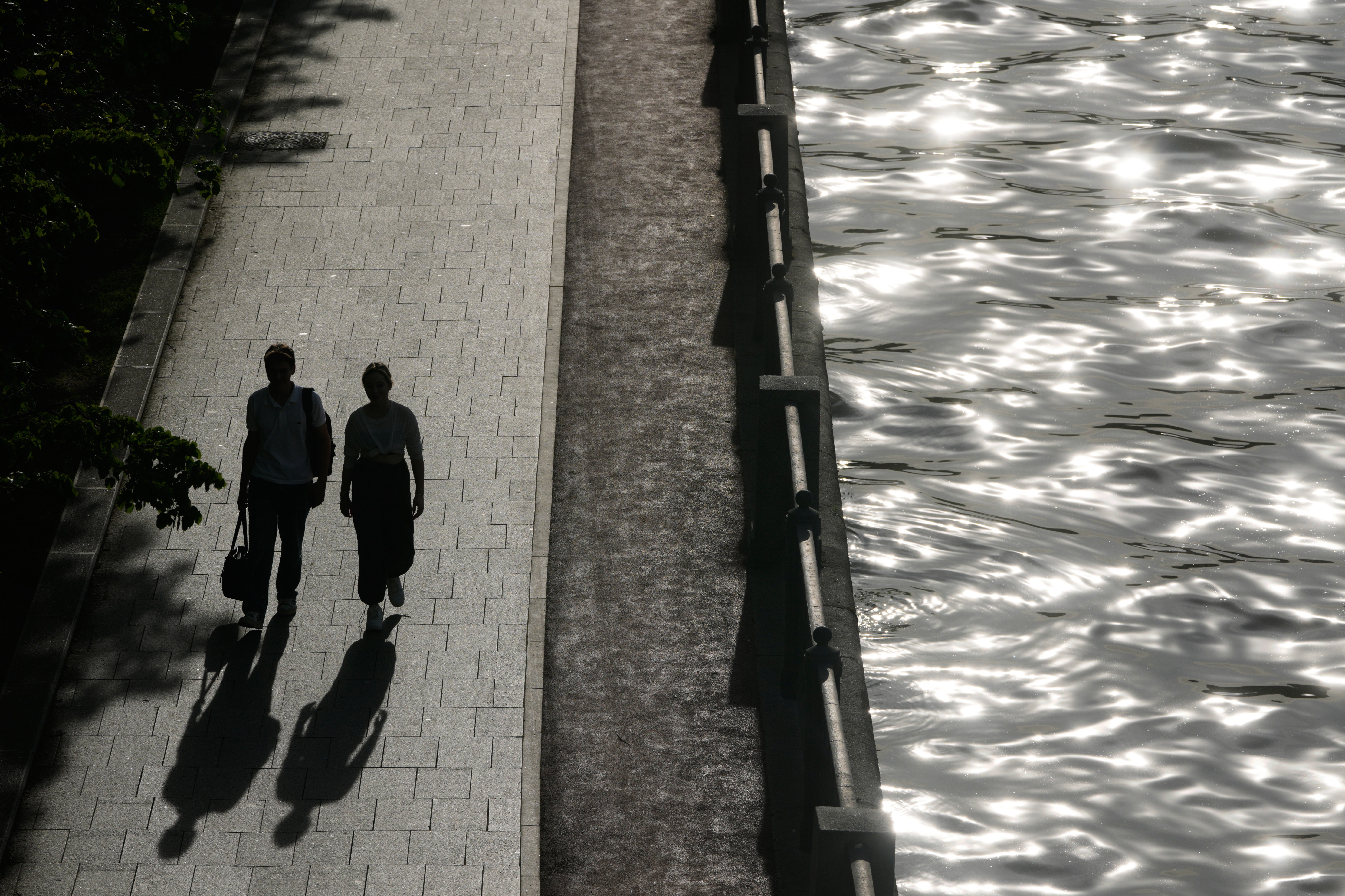People walk by the Moskva River on a sunny day in Moscow (AP)