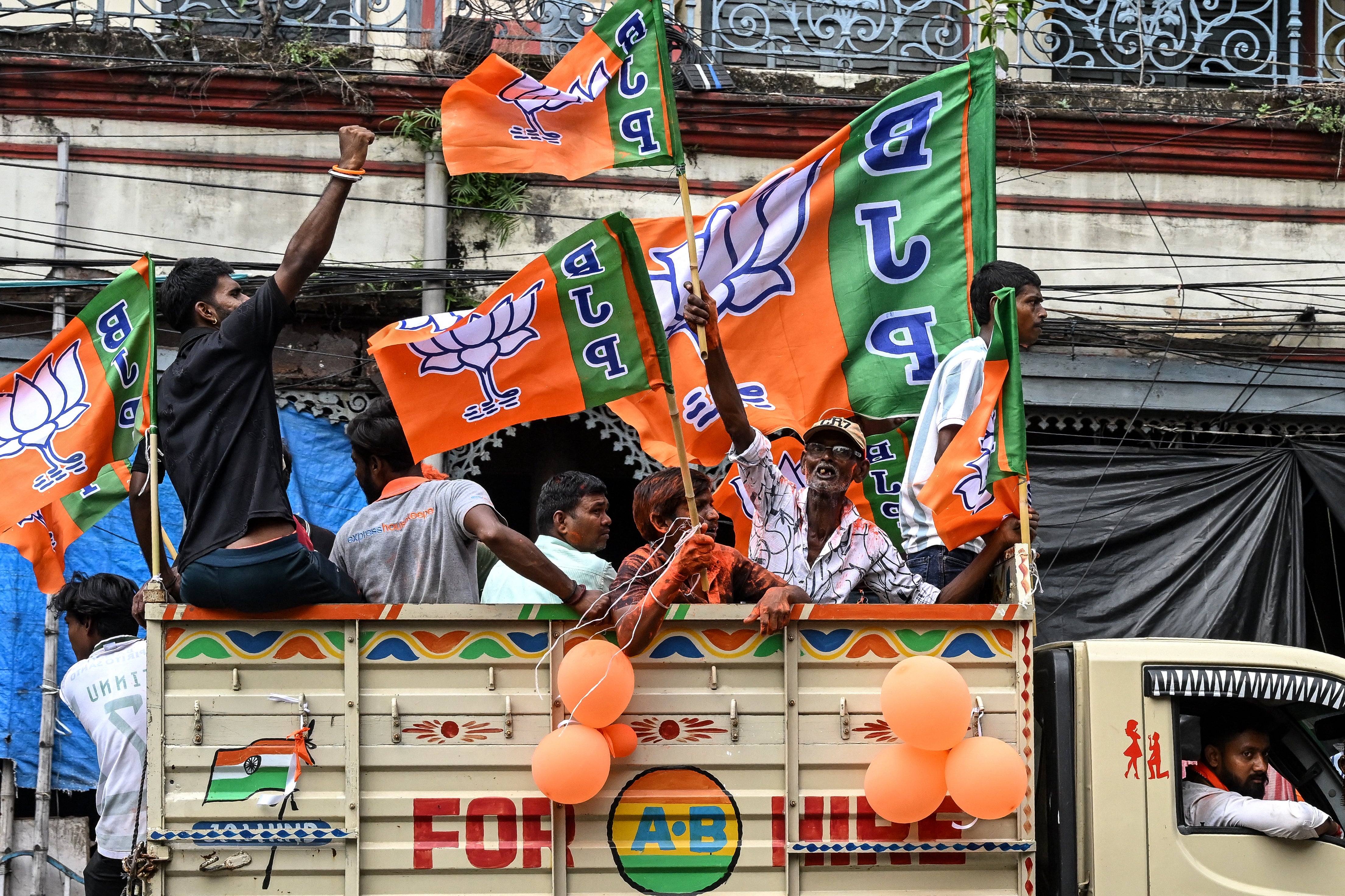 Supporters of the Bharatiya Janata Party (BJP) celebrate with the party flags as they return after attending the swearing-in ceremony of West Bengal's newly-elected Chief Minister Suvendu Adhikari